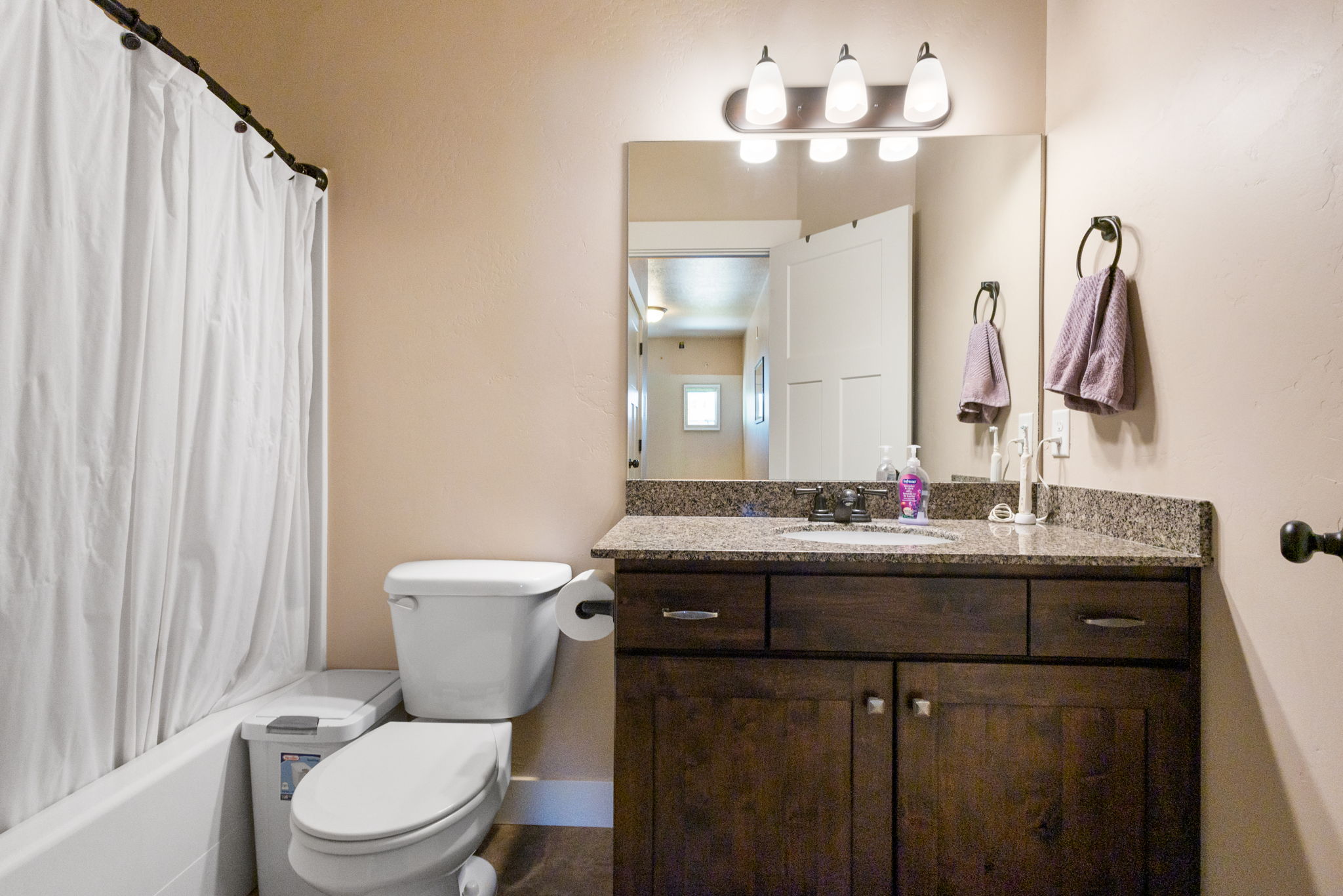 Bathroom vanity featuring a dark wood-finish cabinet with drawers and lower storage, a speckled countertop, and an undermount sink
