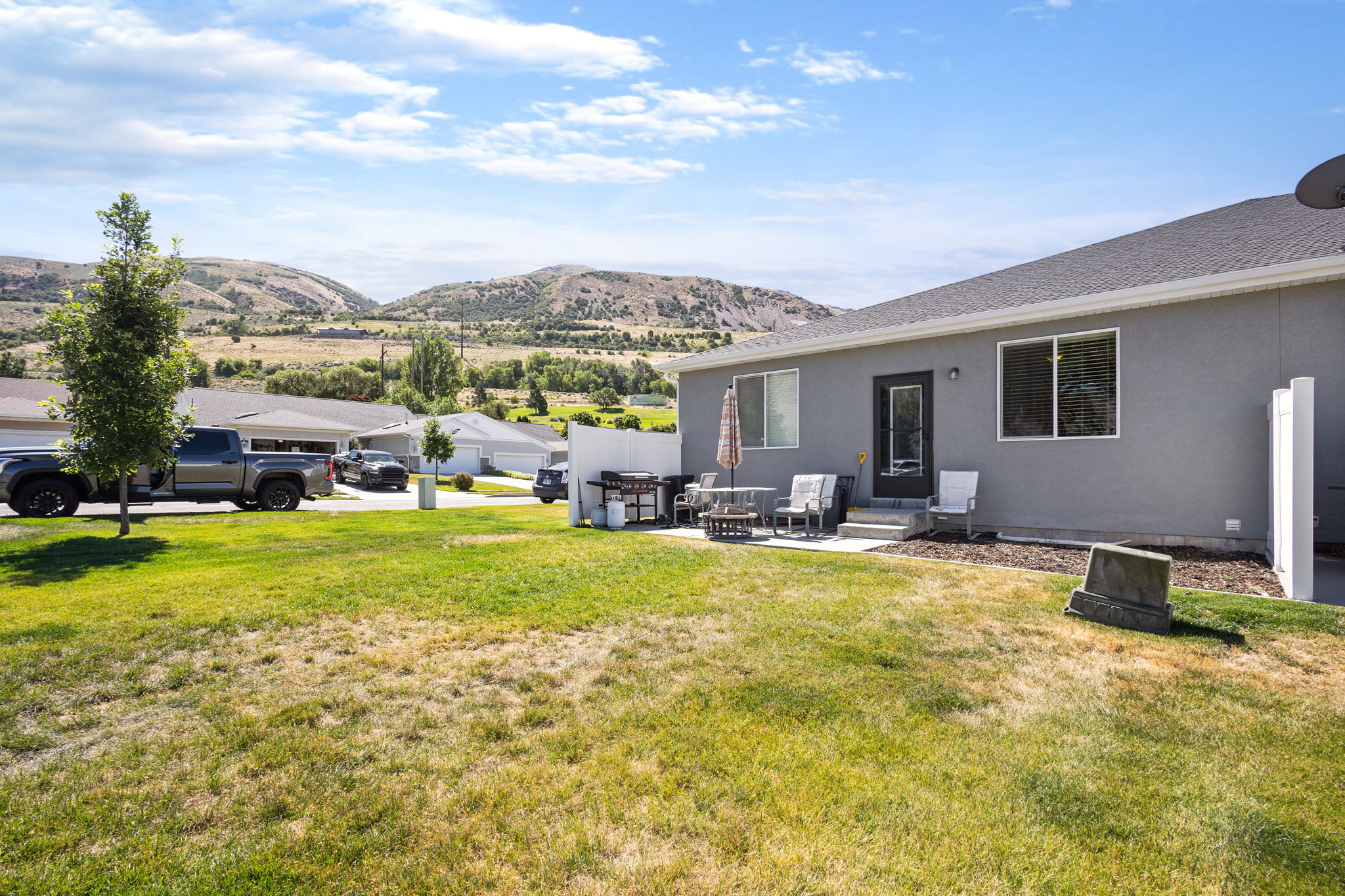 Rear exterior featuring a grey stucco finish, white trim windows, and a dark entry door
