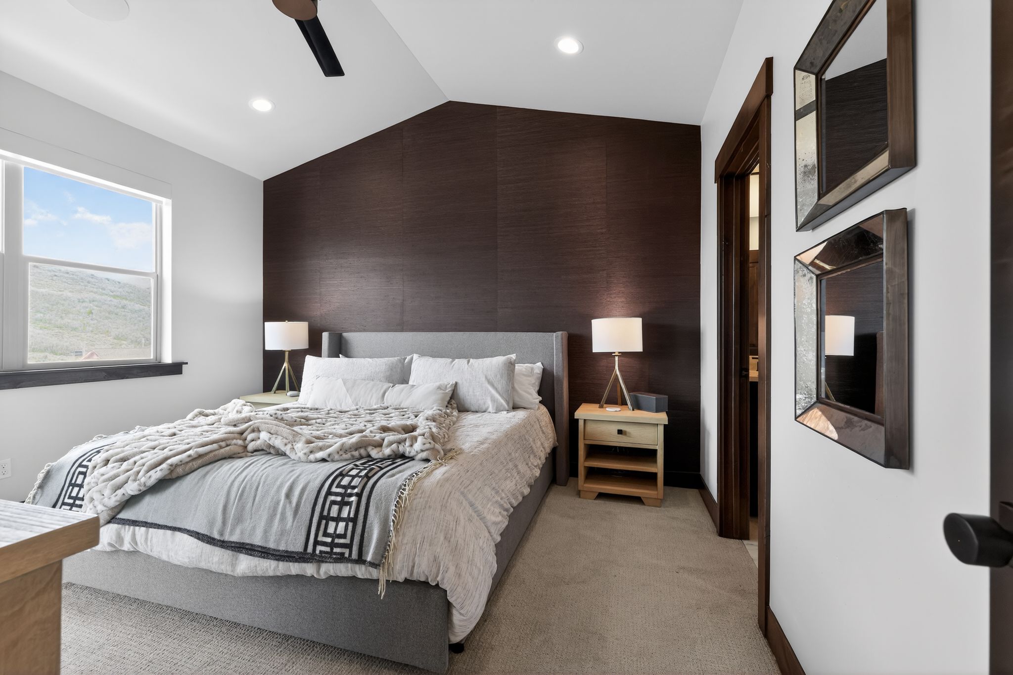 Angled ceiling bedroom with a dark accent wall and recessed lighting