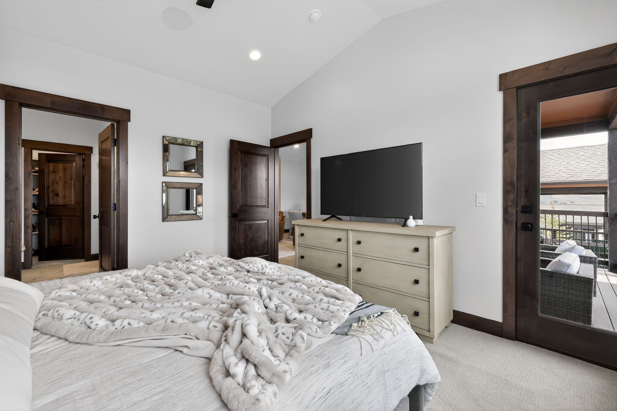 Carpeted bedroom featuring vaulted ceilings, recessed lighting, and dark wood trim