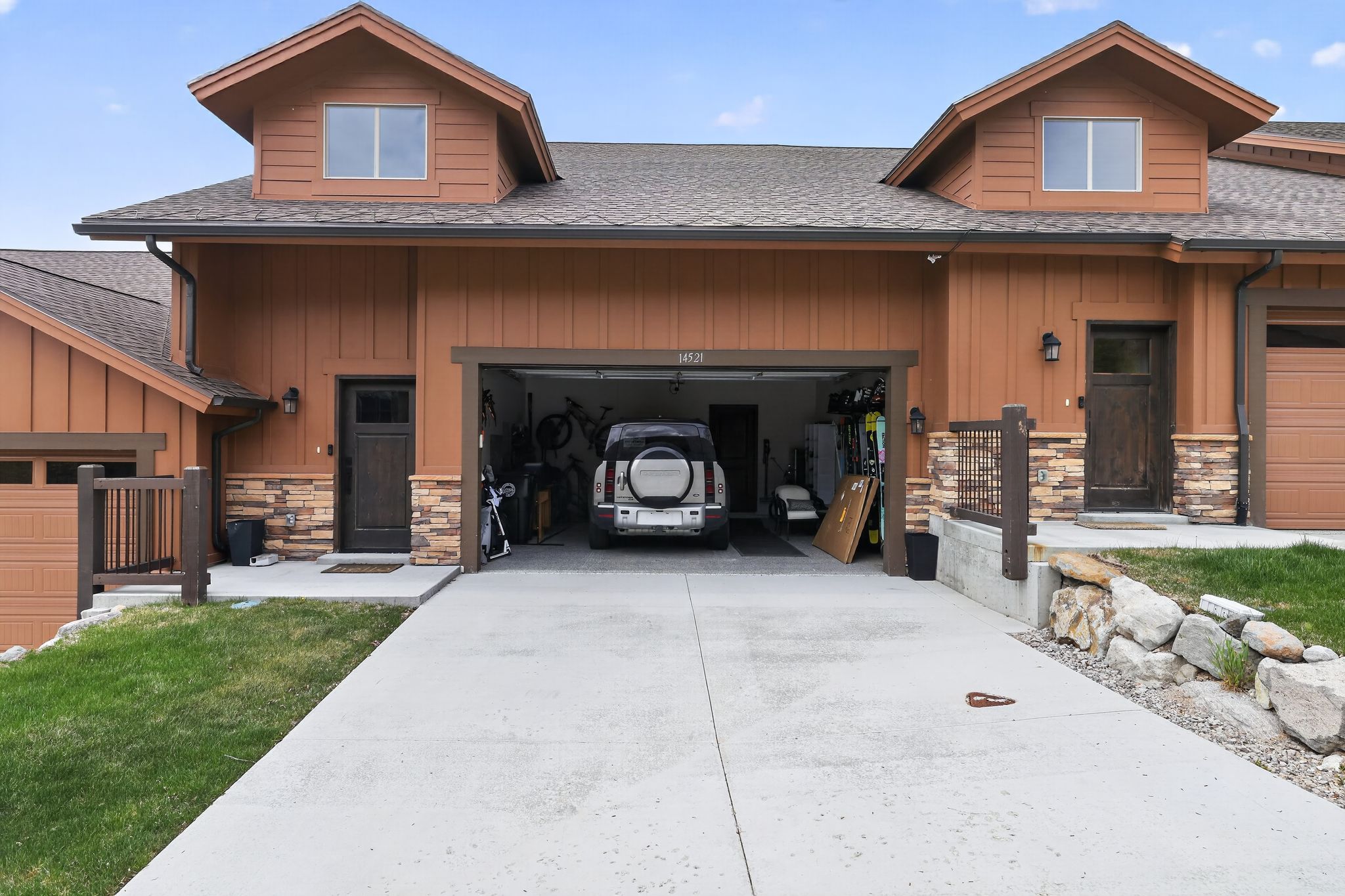 Multi-unit residence featuring dormer windows, natural wood-tone siding, and stone veneer accents