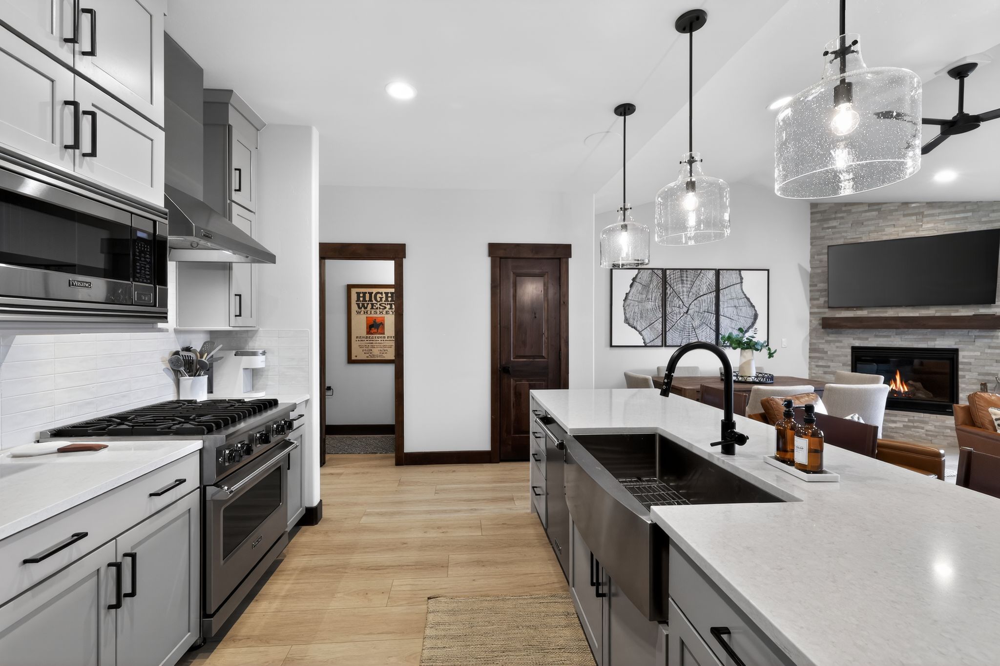 Gourmet kitchen with sleek grey cabinetry, stainless steel appliances, and a large center island featuring a farmhouse sink