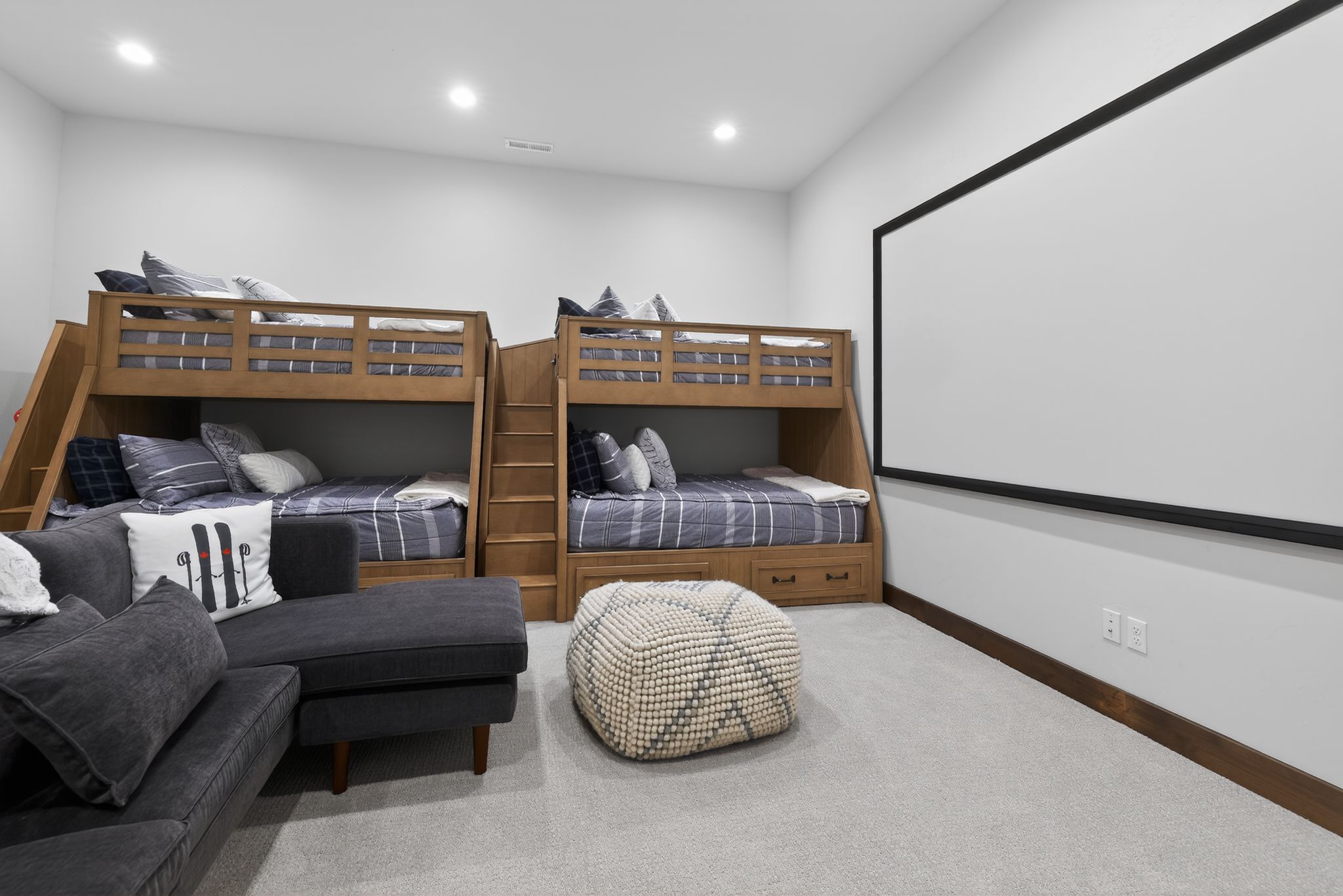 Carpeted room featuring built-in bunk beds with integrated storage, a large projection screen, recessed lighting, and wood baseboards
