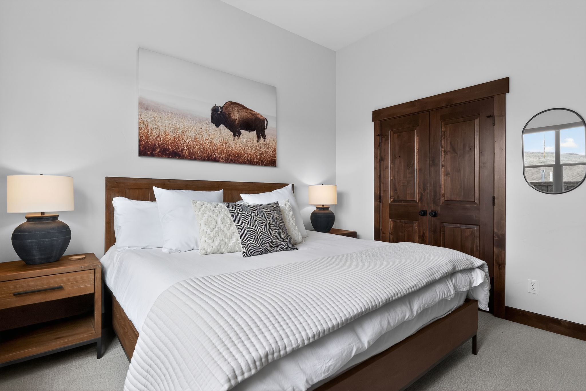 Spacious room featuring wood-finish flooring, white walls, and a built-in closet with dark wood double doors