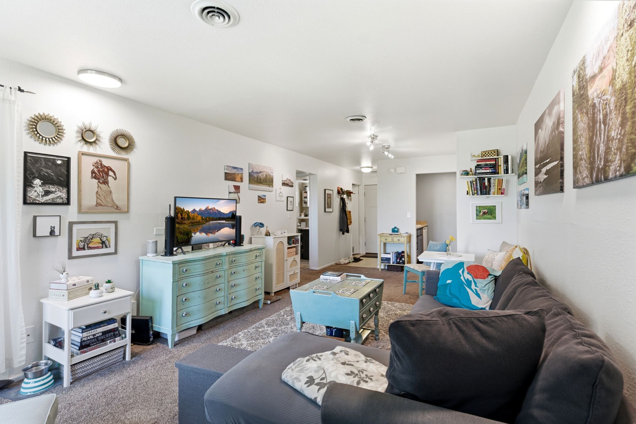 Spacious living area featuring neutral walls, textured carpet flooring, and abundant natural light