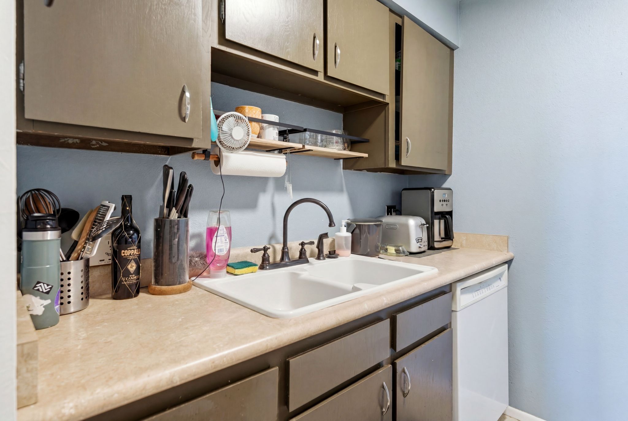 Kitchen featuring a double basin sink, neutral-toned countertops, and painted cabinetry