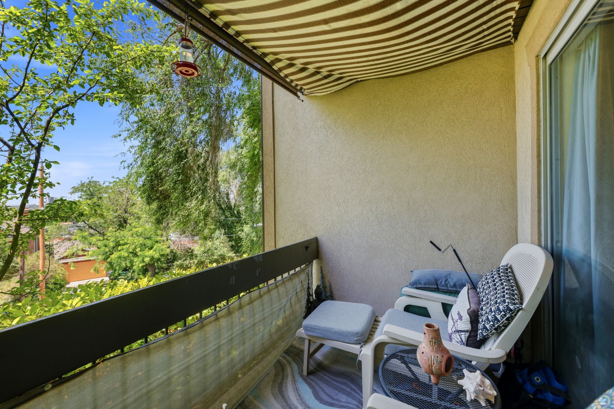 Private balcony featuring a striped awning, stucco exterior, and a sliding glass door