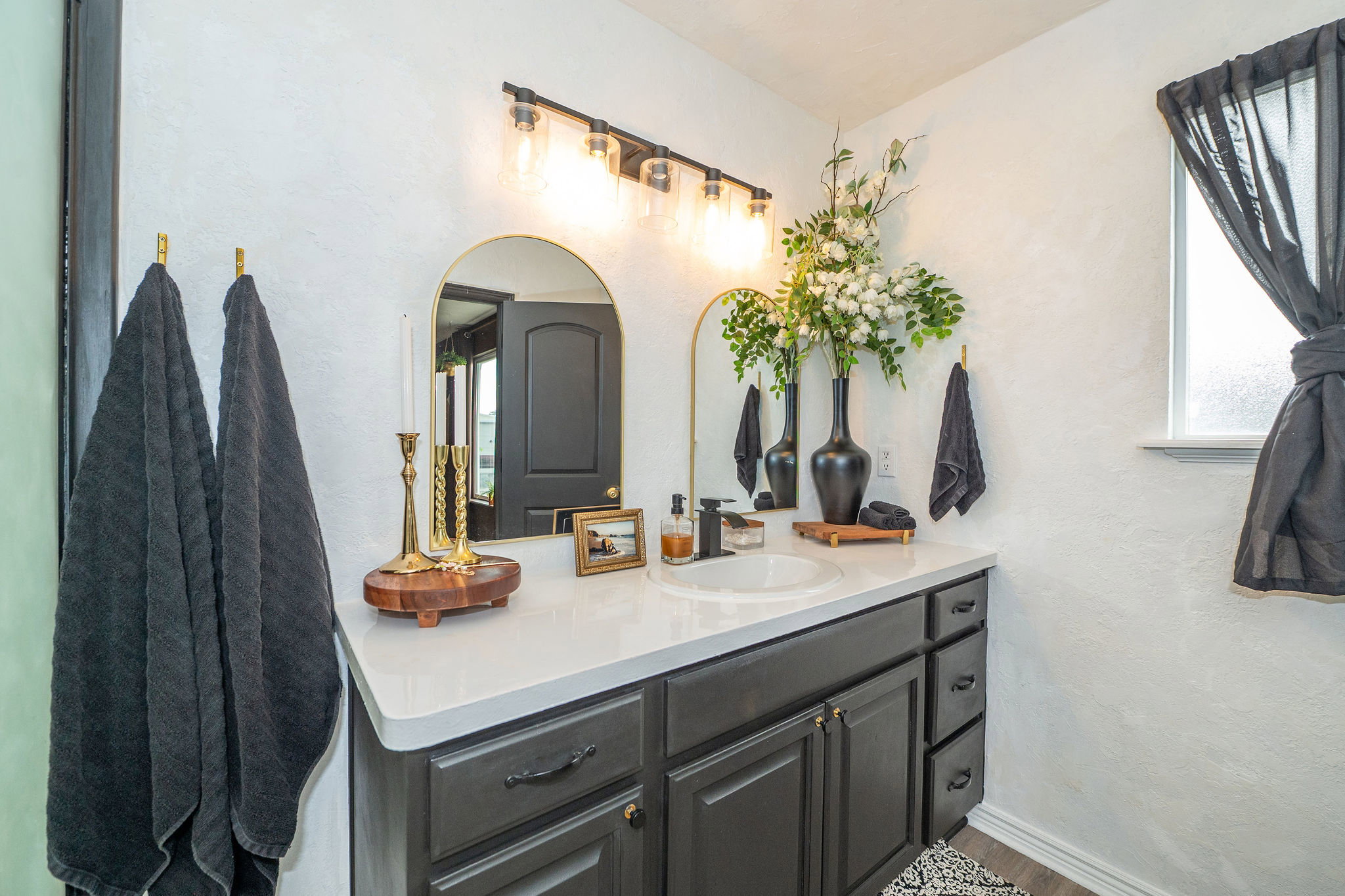 Bathroom vanity featuring a single basin sink, white countertop, and dark cabinetry with drawer storage