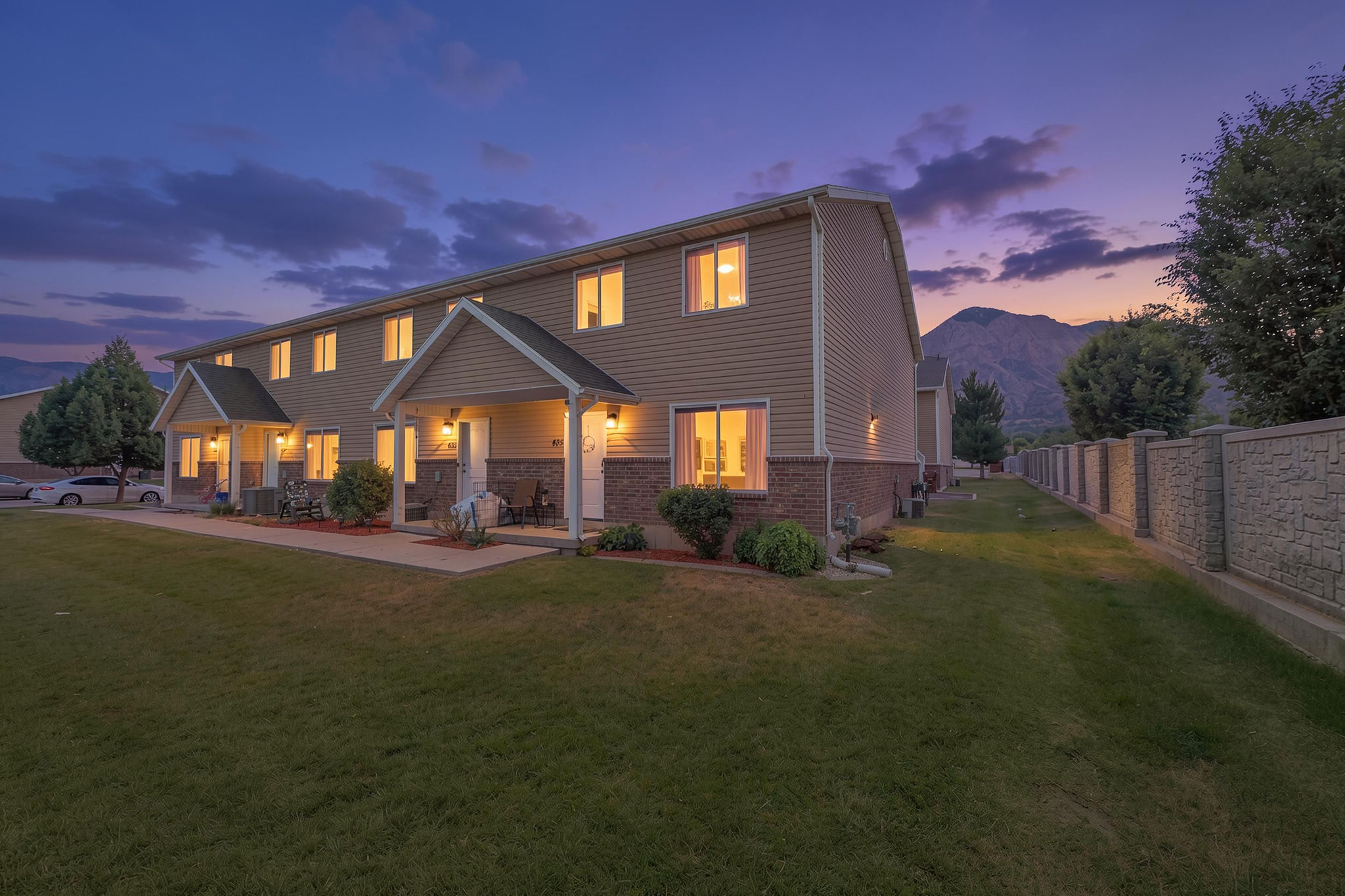 Two-story multi-unit dwelling with light tan siding and a brick-finish lower facade