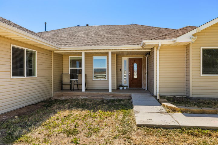 Siding exterior with a covered porch entry featuring a wood-panel front door with a decorative glass insert