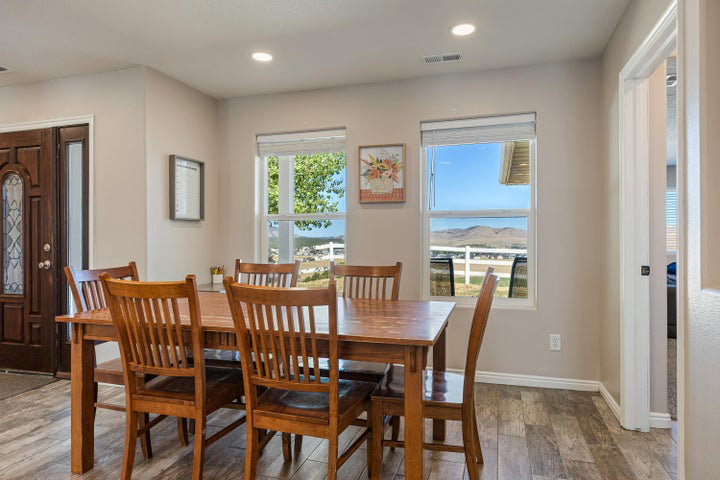Open-concept dining area featuring wood-finish flooring, recessed lighting, and ample natural light from two windows