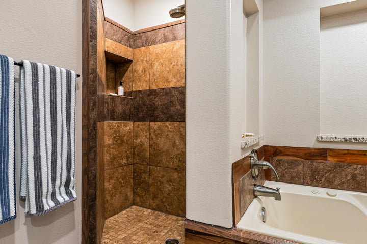 Shower and soaking tub with mixed tile and wood paneling accents