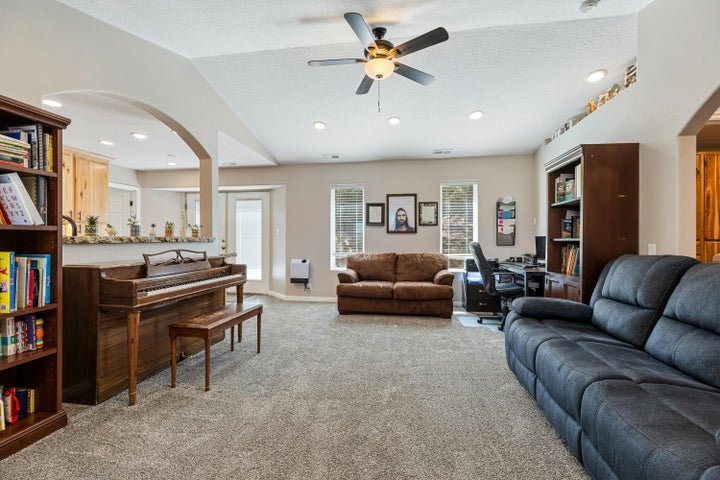 Spacious living area featuring carpet flooring, a ceiling fan, and recessed lighting