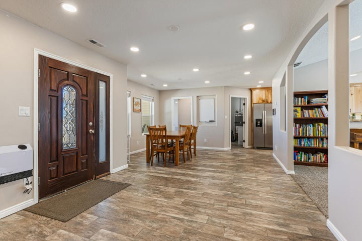 Spacious entry area featuring a decorative wood-panel door with leaded glass, wood-finish flooring, recessed lighting, an arched doorway, and built-in shelving