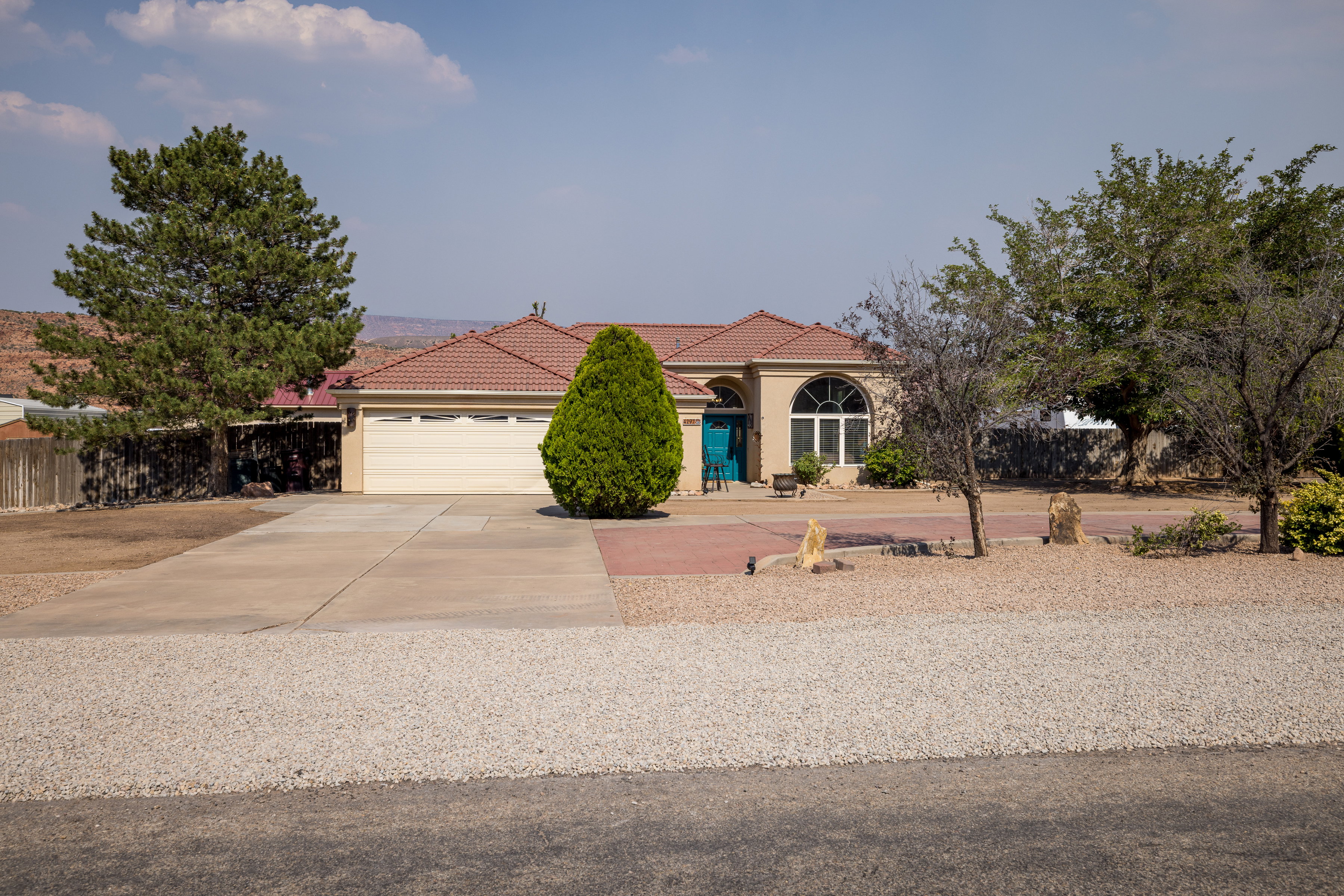 Southwestern-style residence featuring a terracotta-tiled roof and an attached garage with a light-colored door