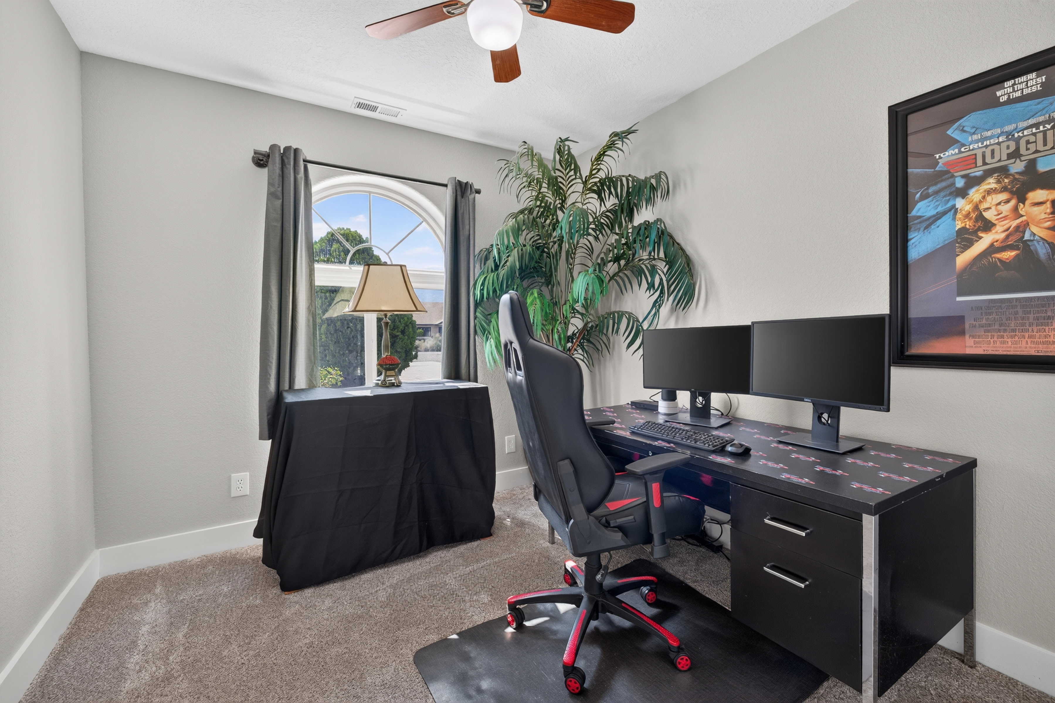 Room featuring light gray walls, plush carpet flooring, a ceiling fan with integrated lighting, and a prominent arched window
