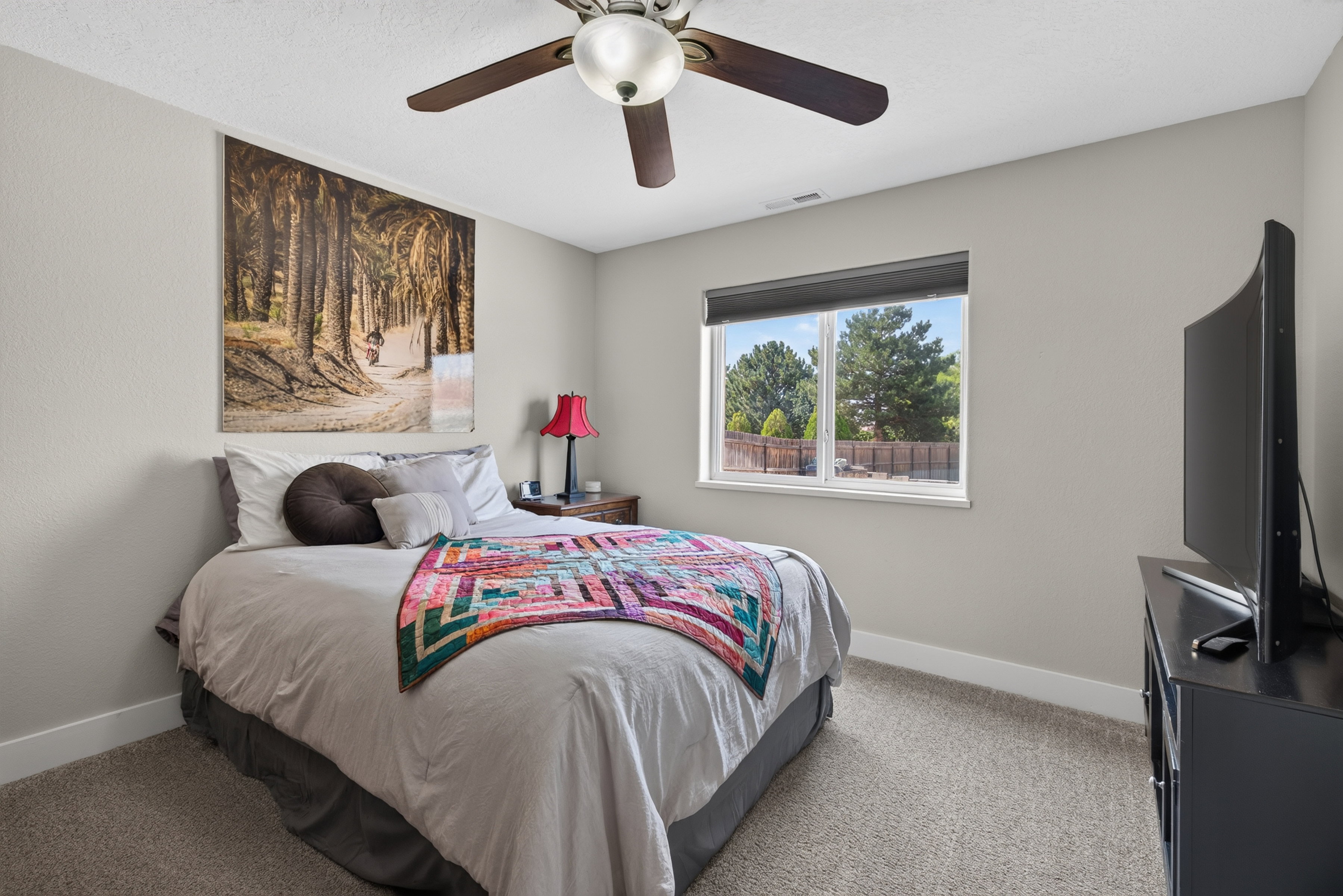 Carpeted room featuring a ceiling fan with integrated lighting, a window with a roller shade, and neutral wall tones