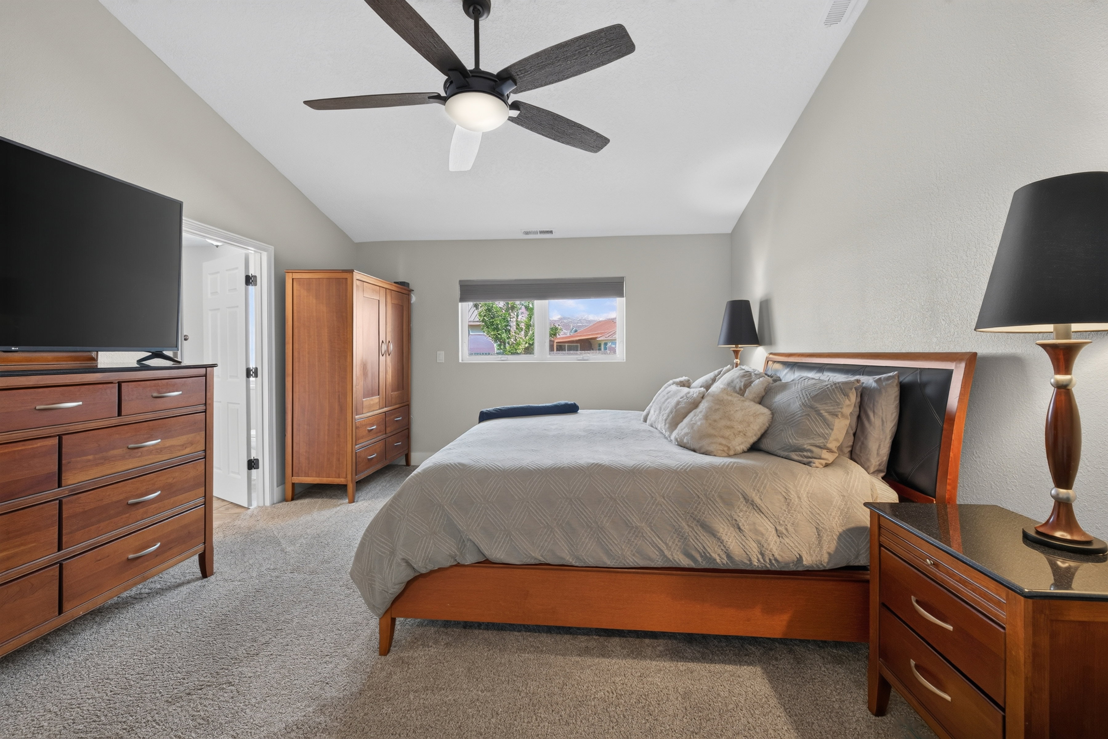 Carpeted room featuring a ceiling fan with integrated lighting, a window with a roller shade, and light gray painted walls