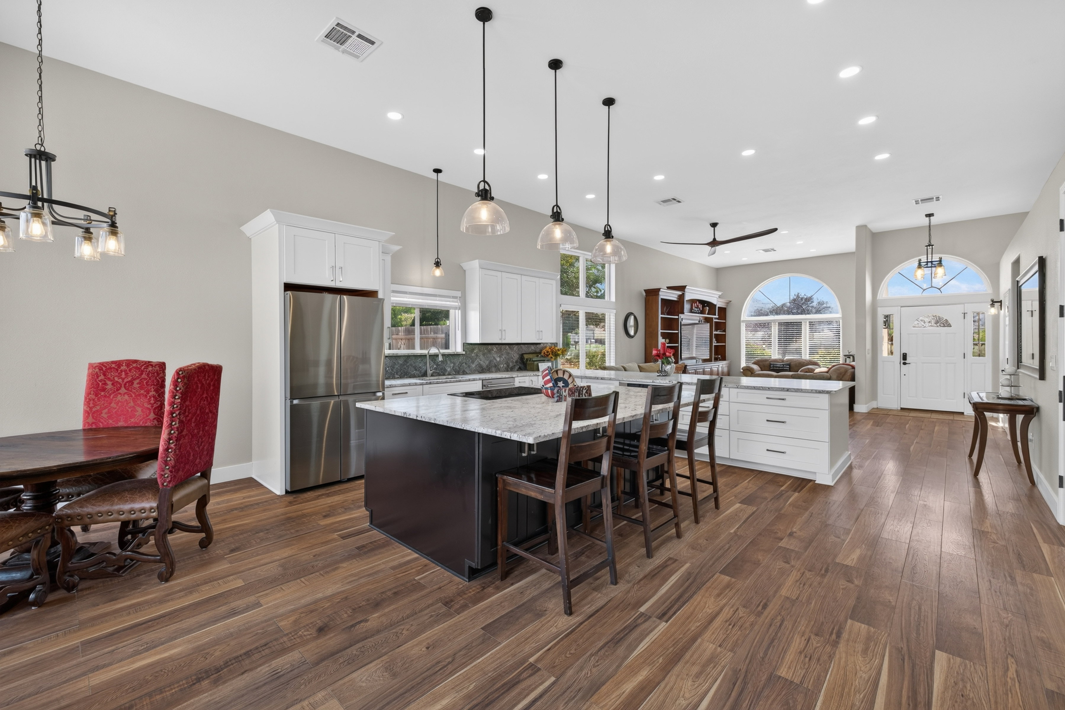 Open-concept living space with wood-finish flooring, vaulted ceilings, and recessed lighting