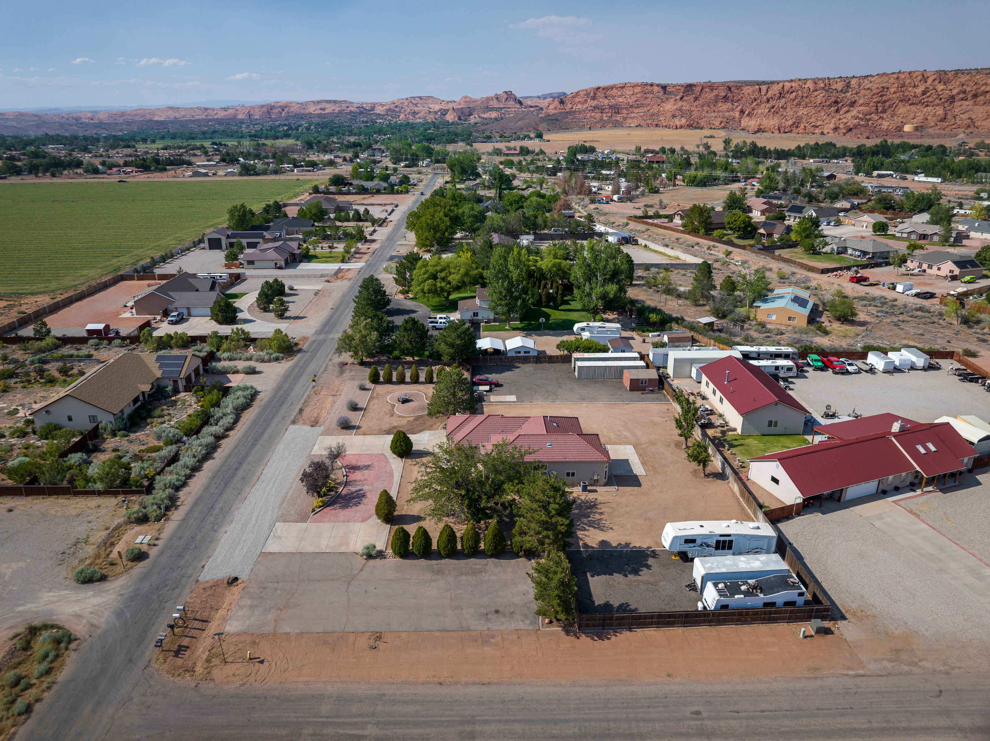 Expansive parcel featuring multiple buildings with red roofs, a large gravel lot, and paved access
