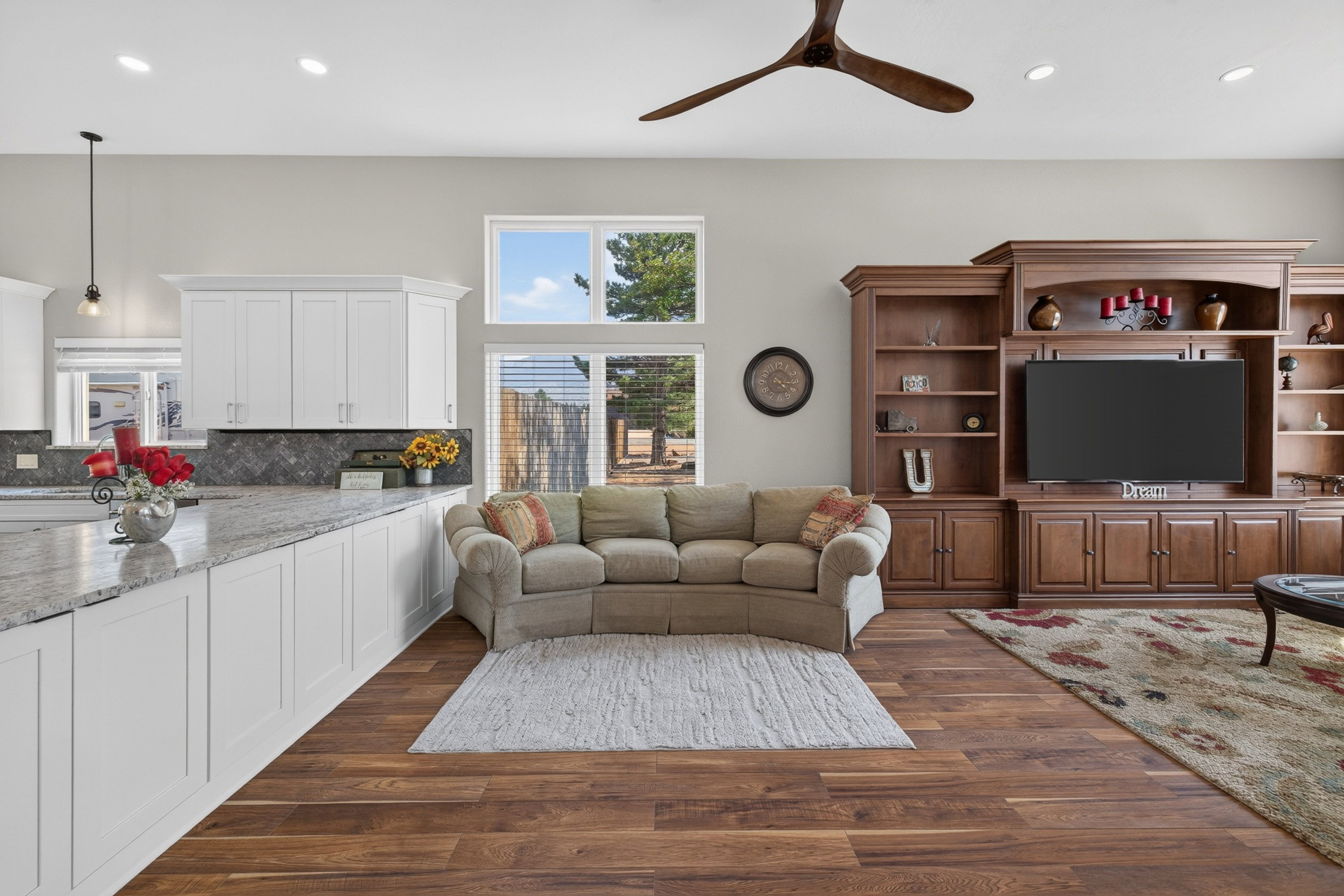 Open-concept living space featuring wood-finish flooring, a built-in media center, recessed lighting, and a contemporary ceiling fan