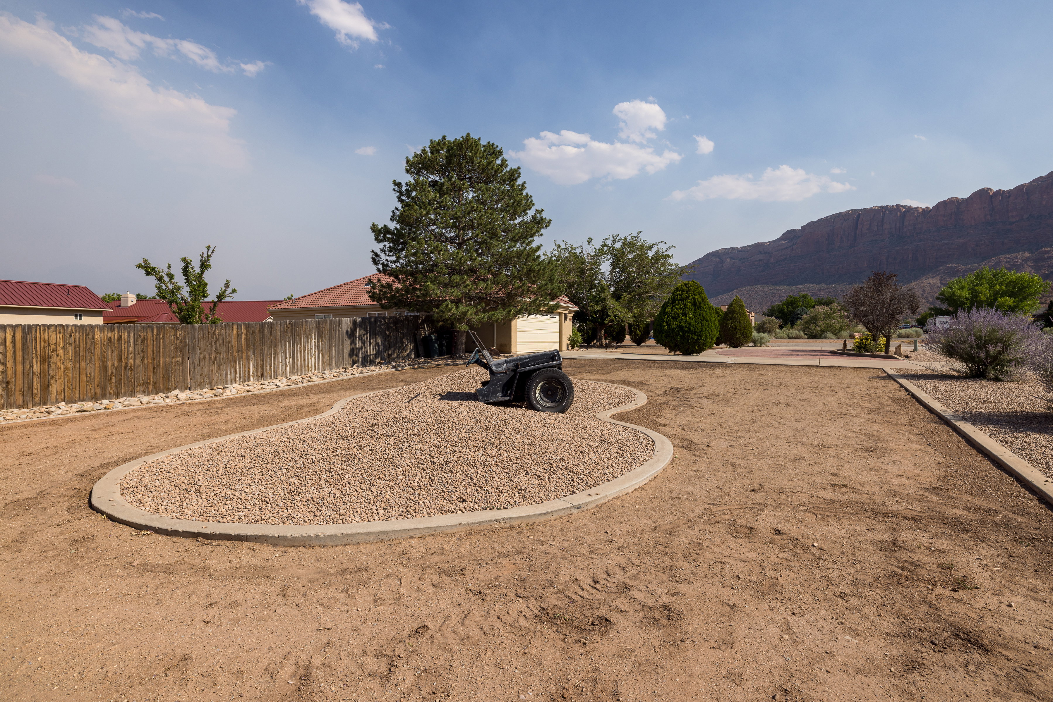 Expansive front yard featuring a defined gravel bed and a large shade tree