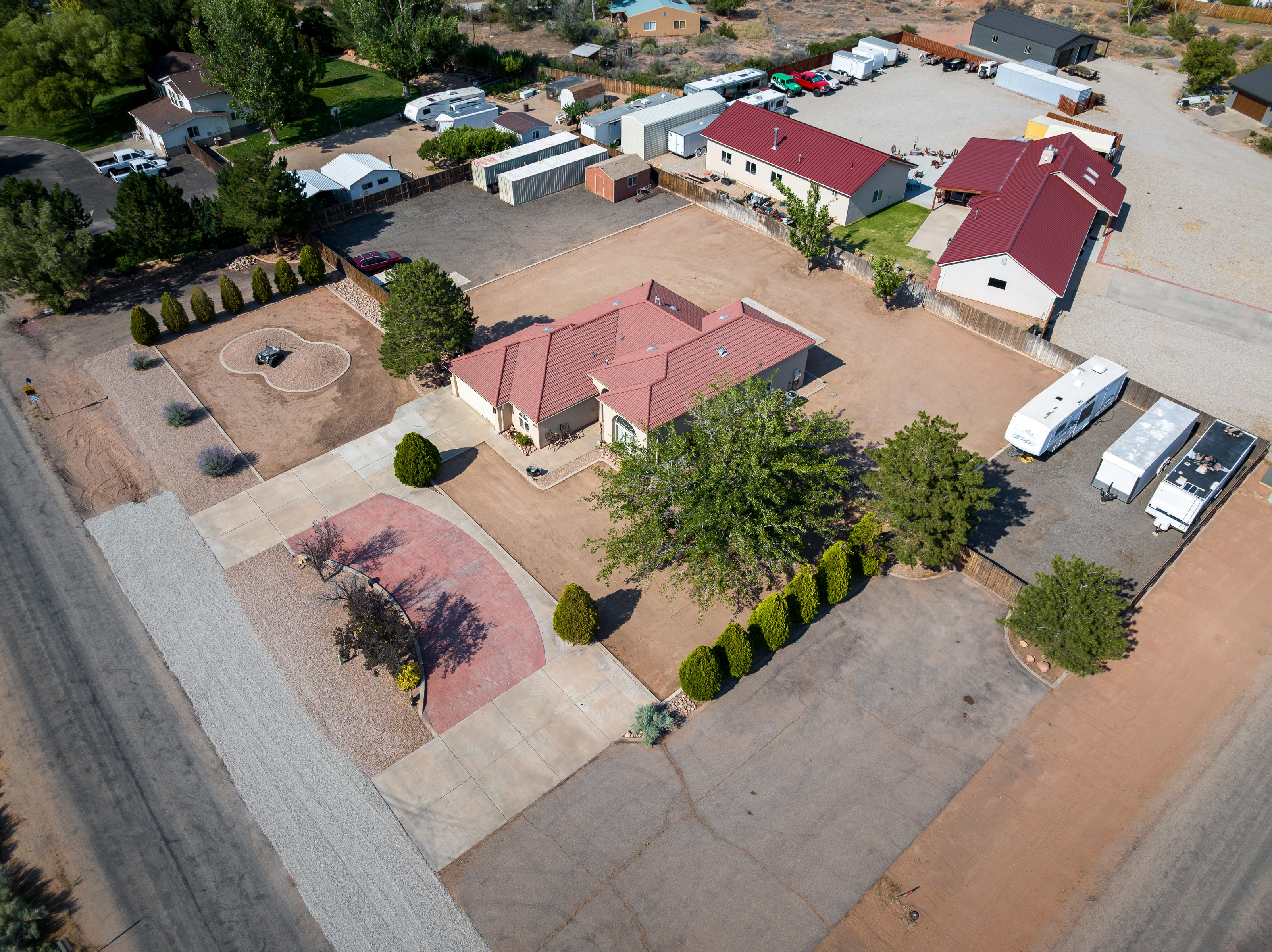 Expansive property featuring a central residence with a red-tiled roof, multiple outbuildings, and extensive paved and gravel parking areas