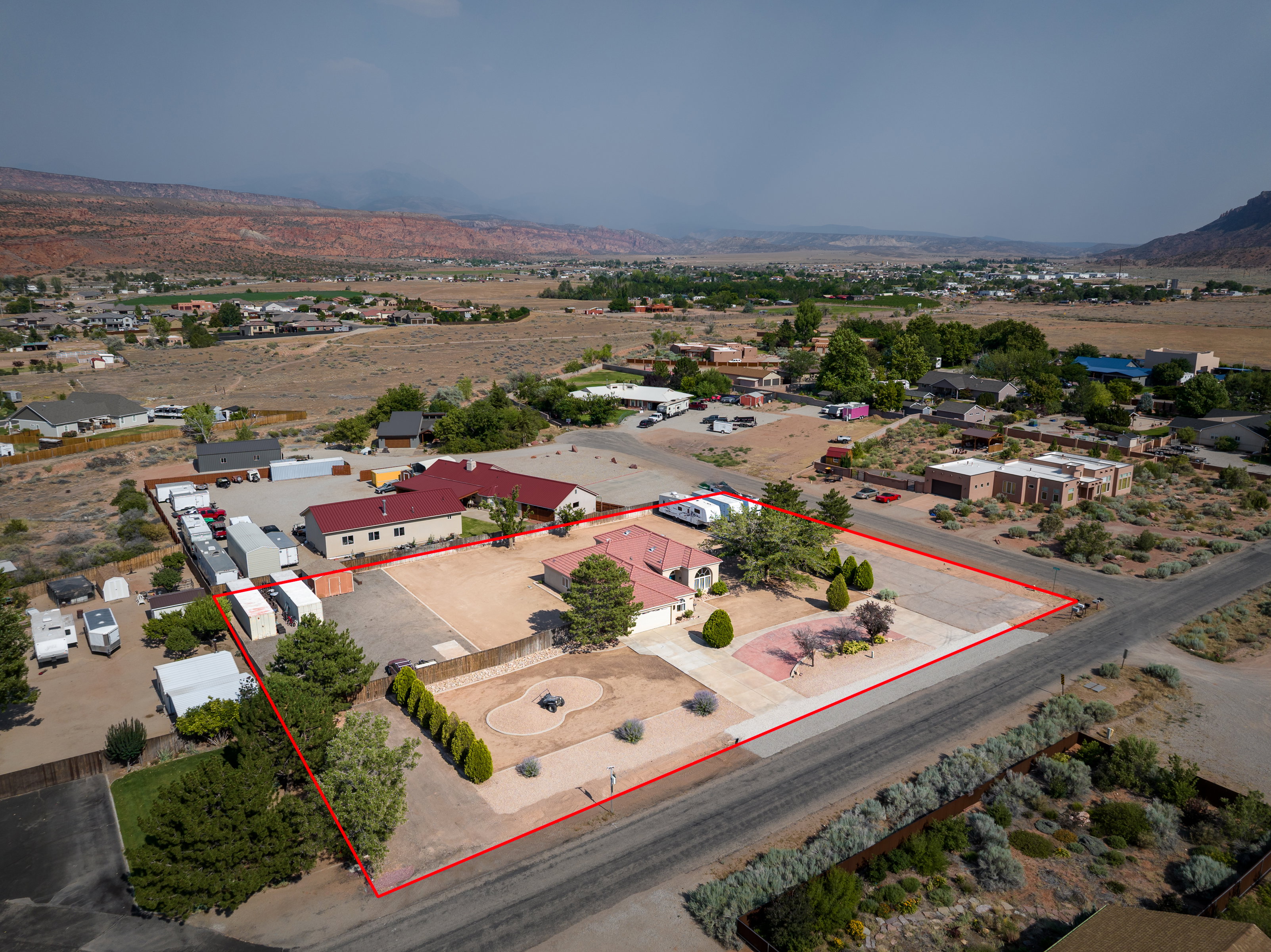 Expansive property featuring two distinct building structures, a large paved driveway, and a spacious gravel lot