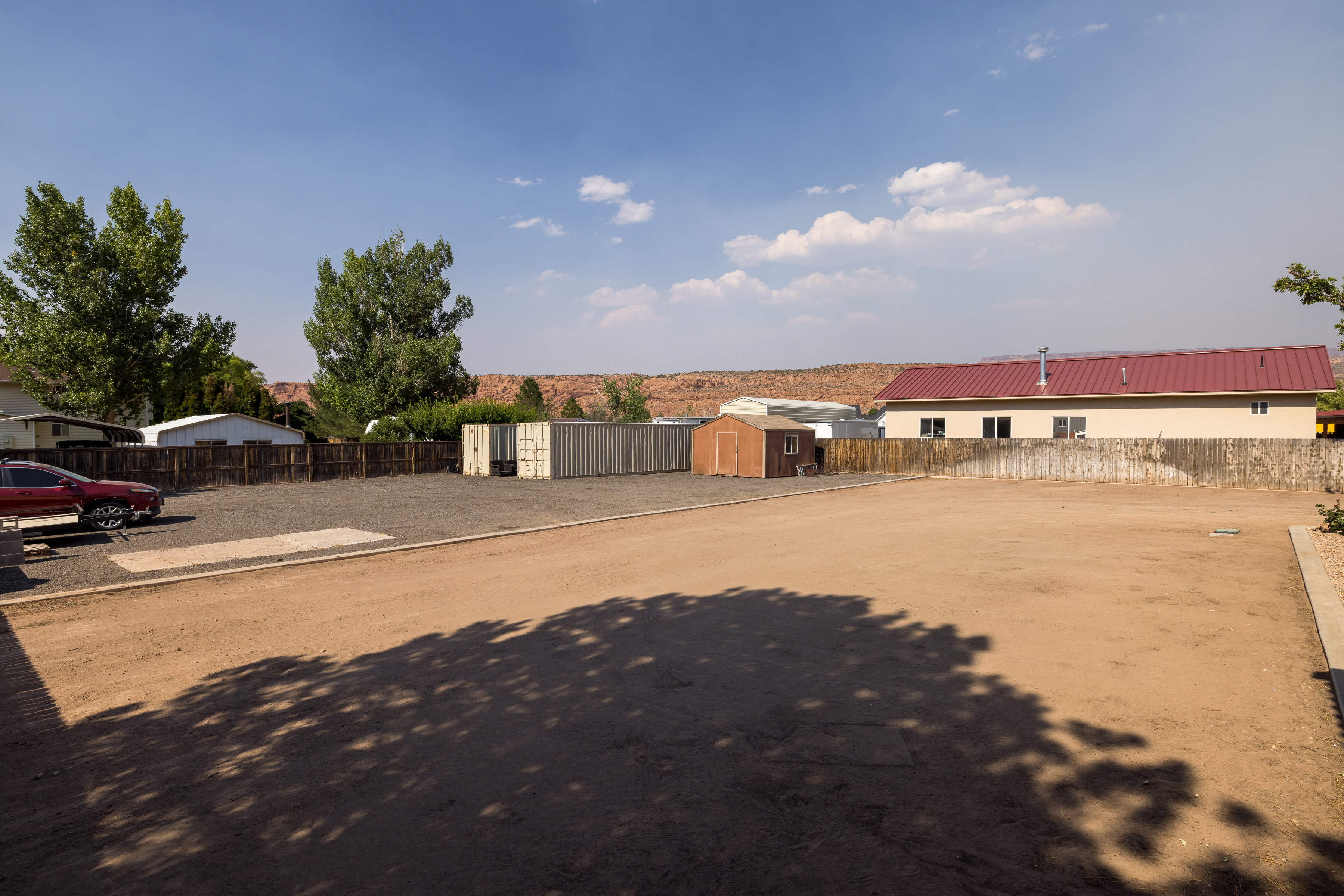 Expansive outdoor space featuring a large dirt lot and gravel parking area
