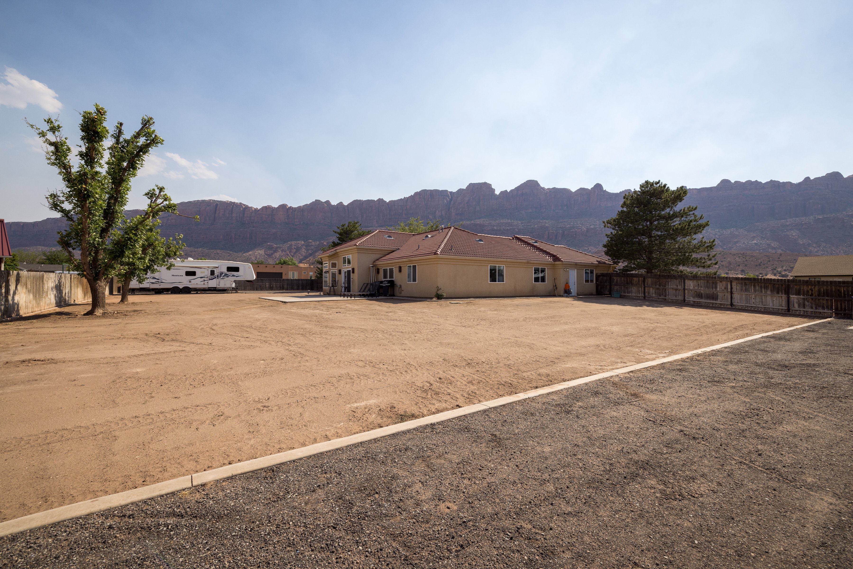 Expansive property featuring a gravel parking area, a large unlandscaped yard, and mountain scenery