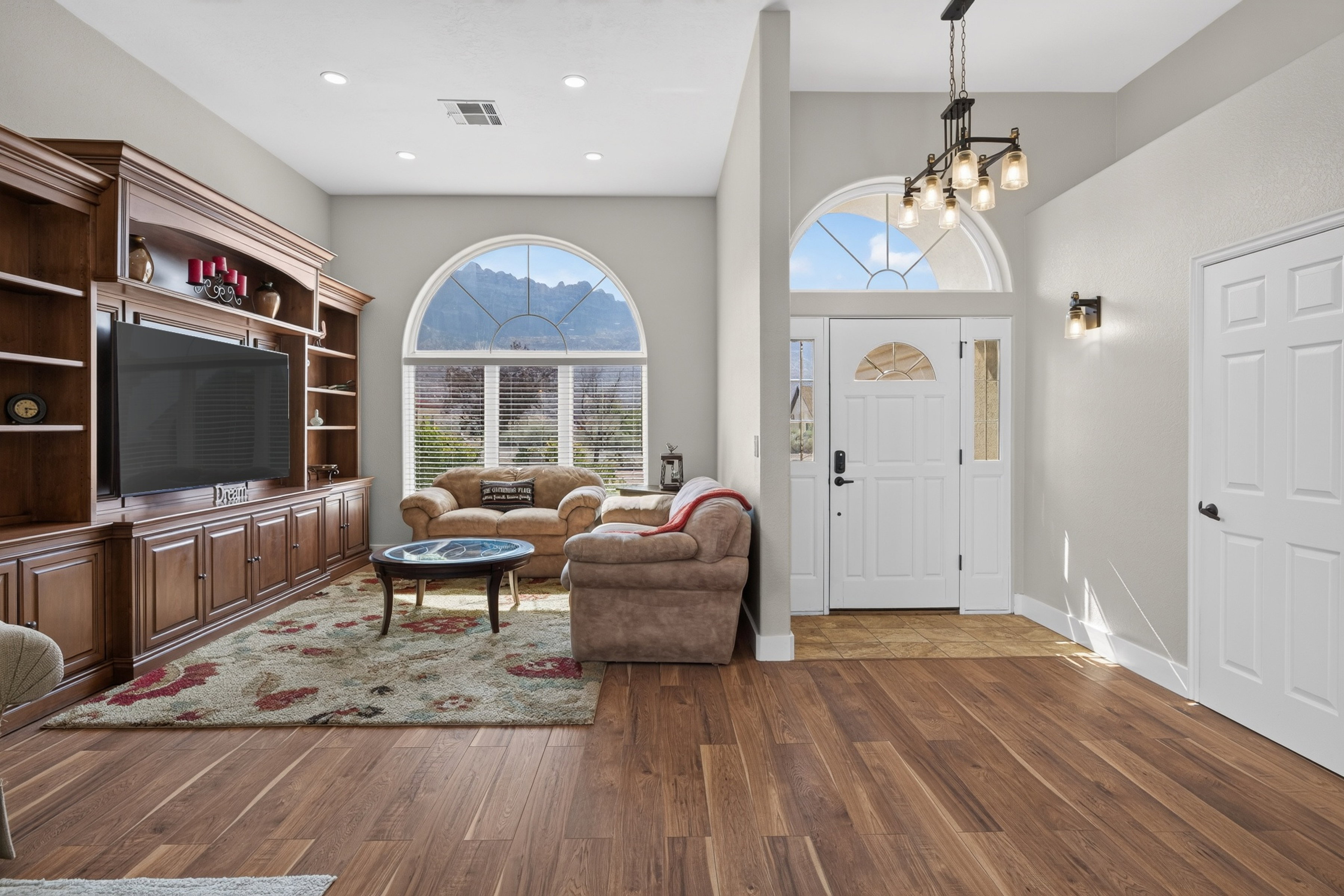 Spacious living area featuring rich wood-finish flooring and a built-in entertainment center with extensive cabinetry