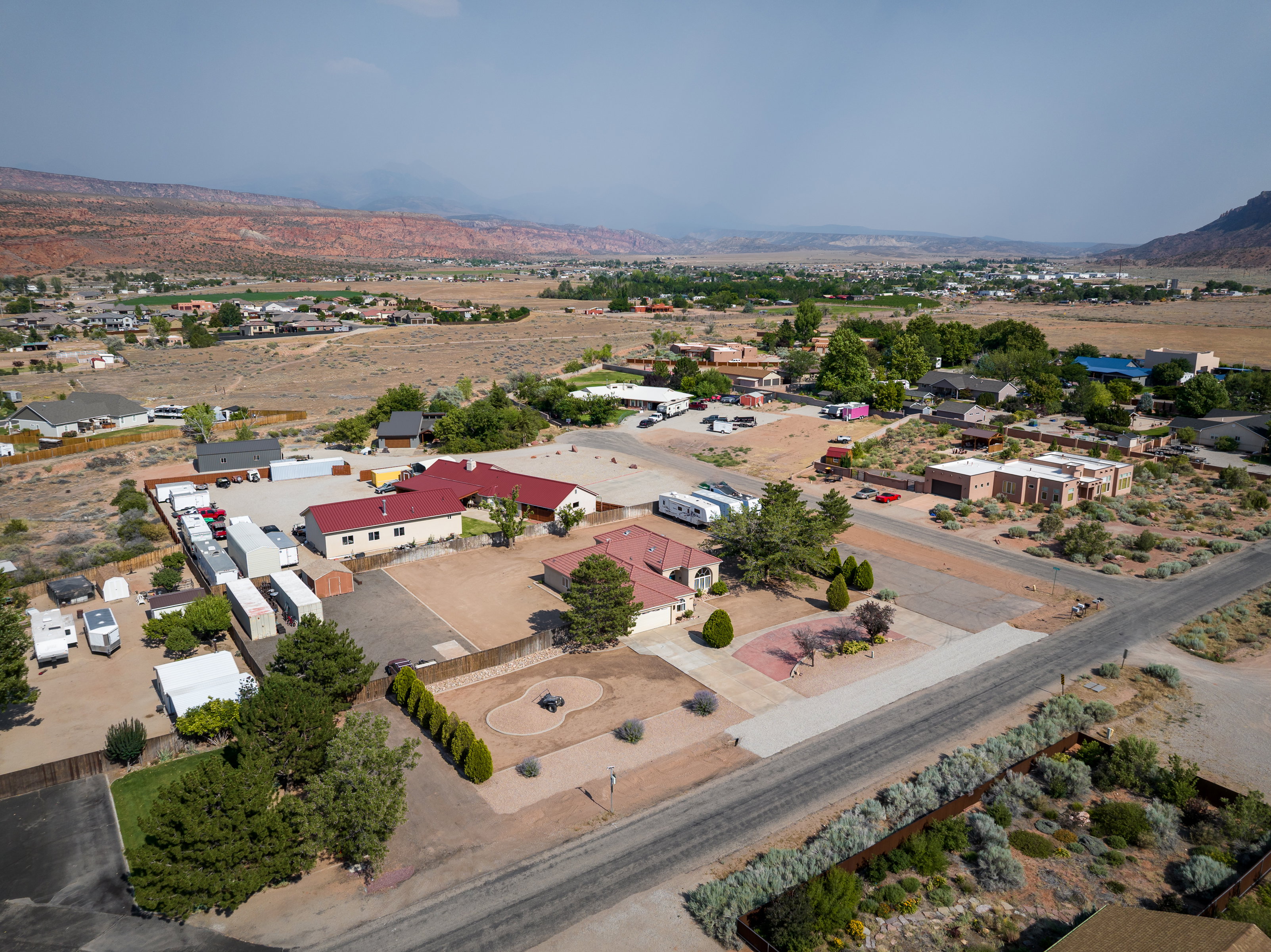 Expansive property featuring multiple structures, paved driveways, and surrounding natural landscaping