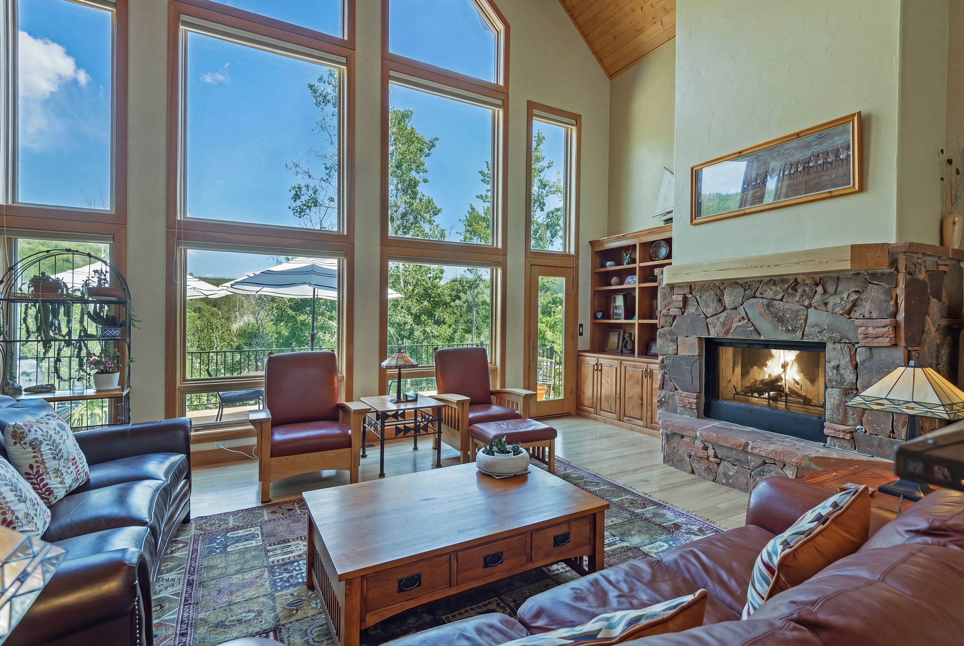 Spacious living area featuring a stone-clad fireplace with wood mantle, vaulted ceilings with wood-finish paneling, and wood-finish flooring