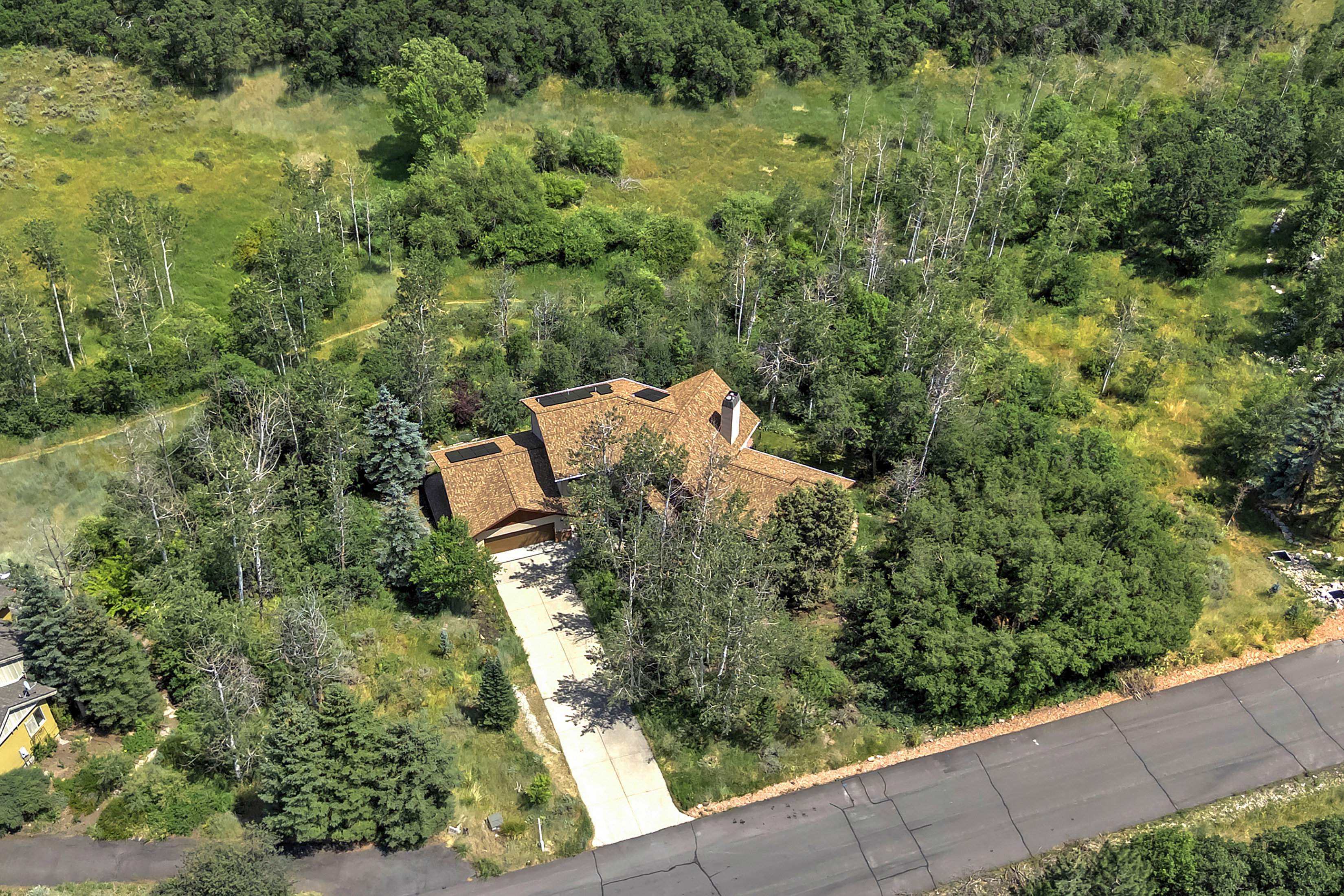 Elevated property with a multi-gabled roofline and attached garage, surrounded by mature trees