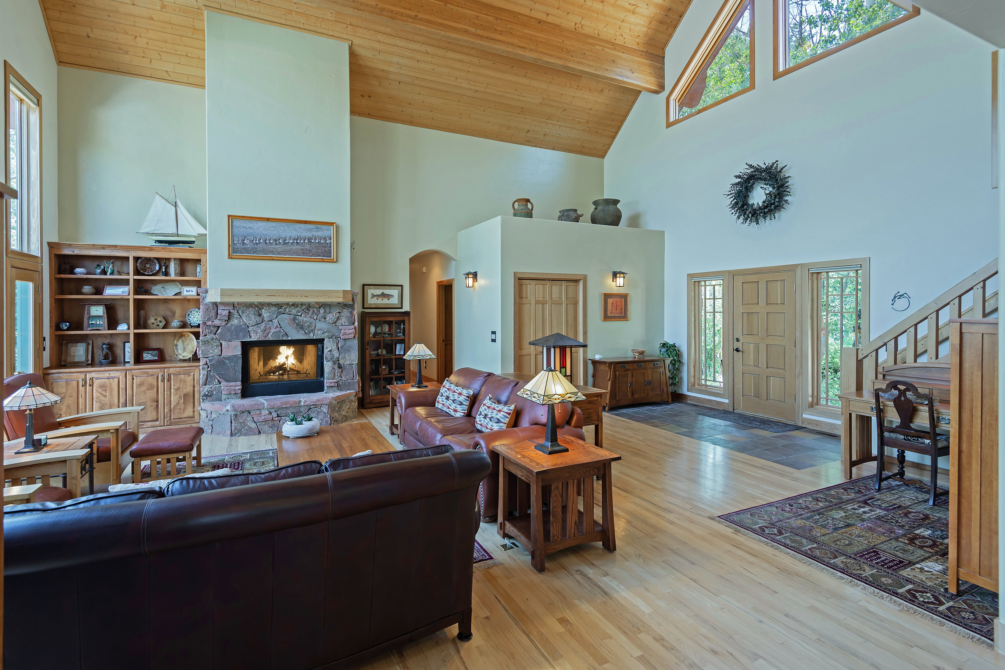 Vaulted wood-paneled ceilings over a spacious room featuring a stone fireplace