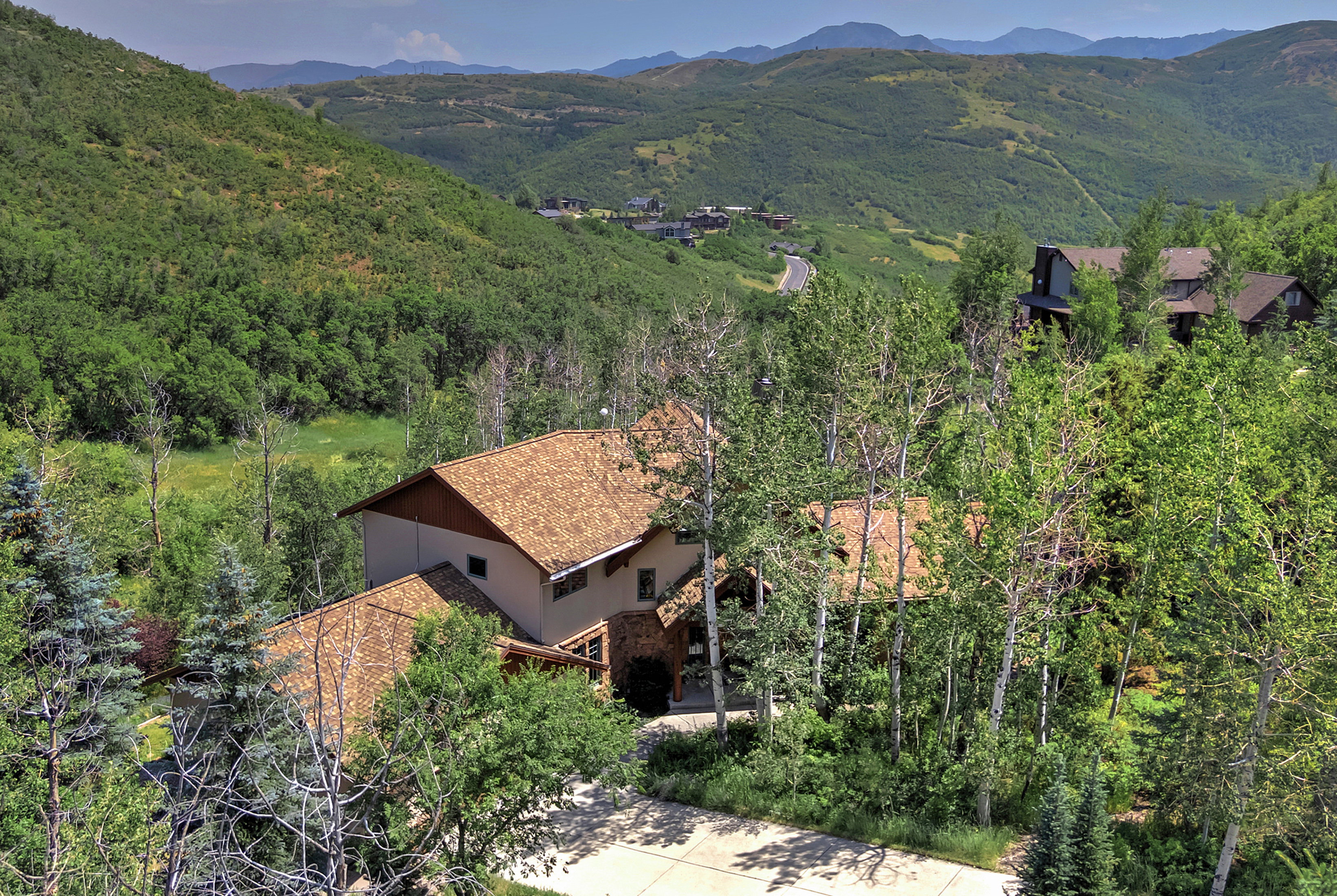 Expansive property featuring a multi-level residence with a shingle roof and a concrete driveway