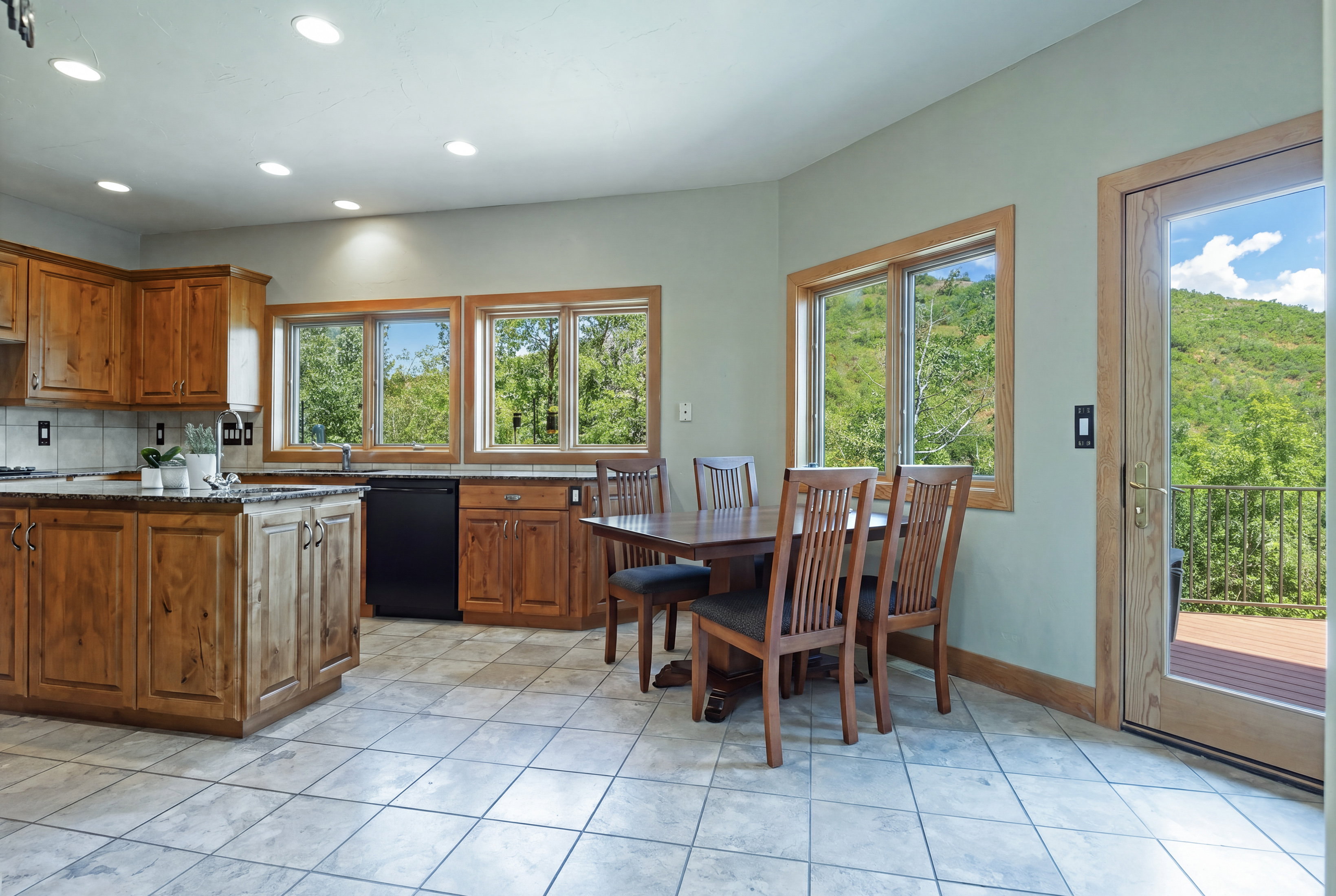Kitchen and dining area featuring wood cabinetry, granite-style countertops, and a tile backsplash