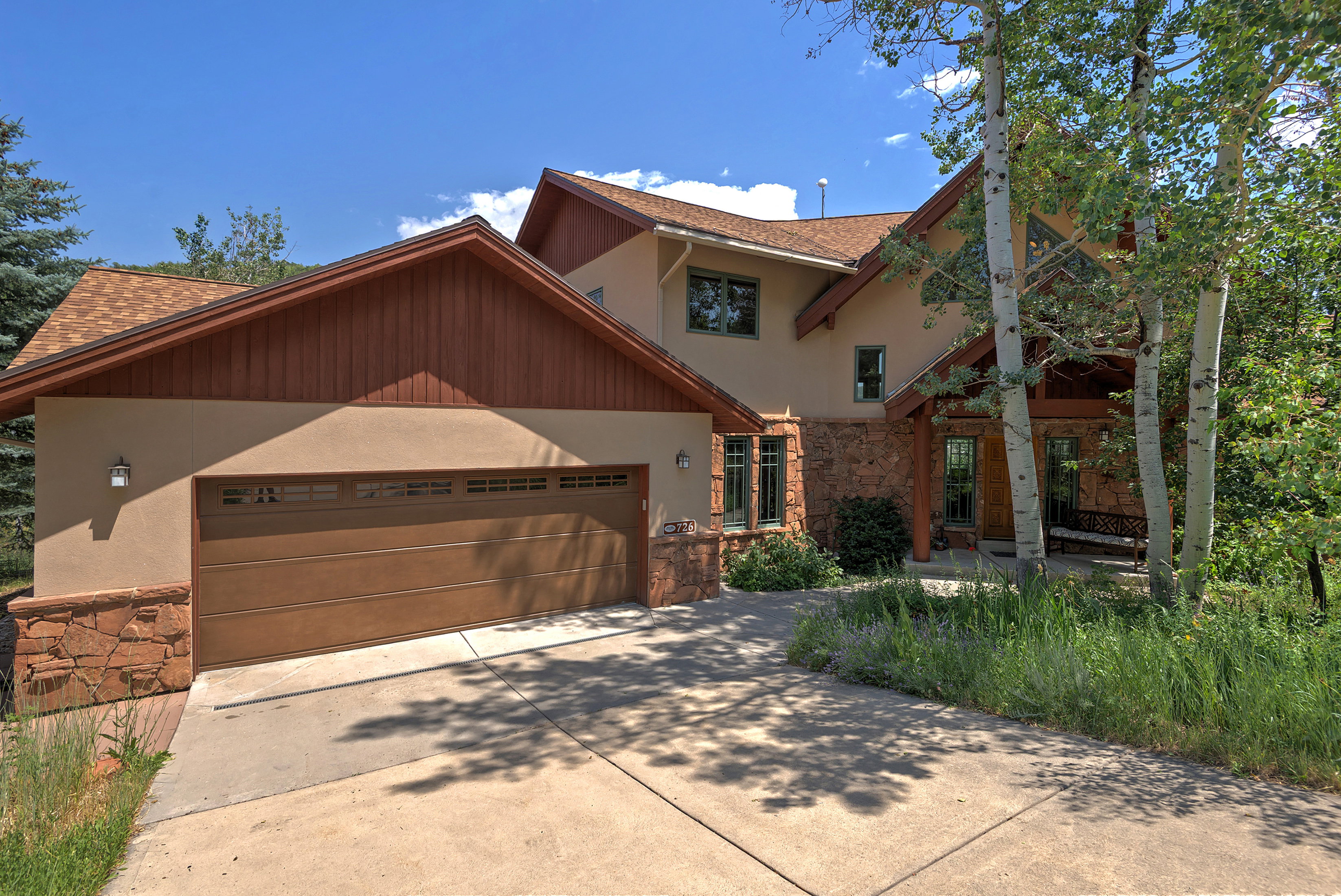 Stucco exterior featuring extensive stone detailing and wood accents