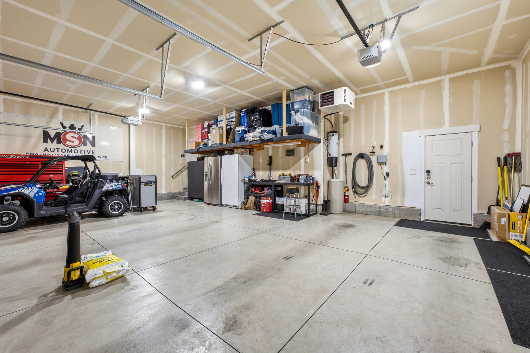 Spacious garage featuring a concrete floor, overhead lighting, and an overhead garage door opener