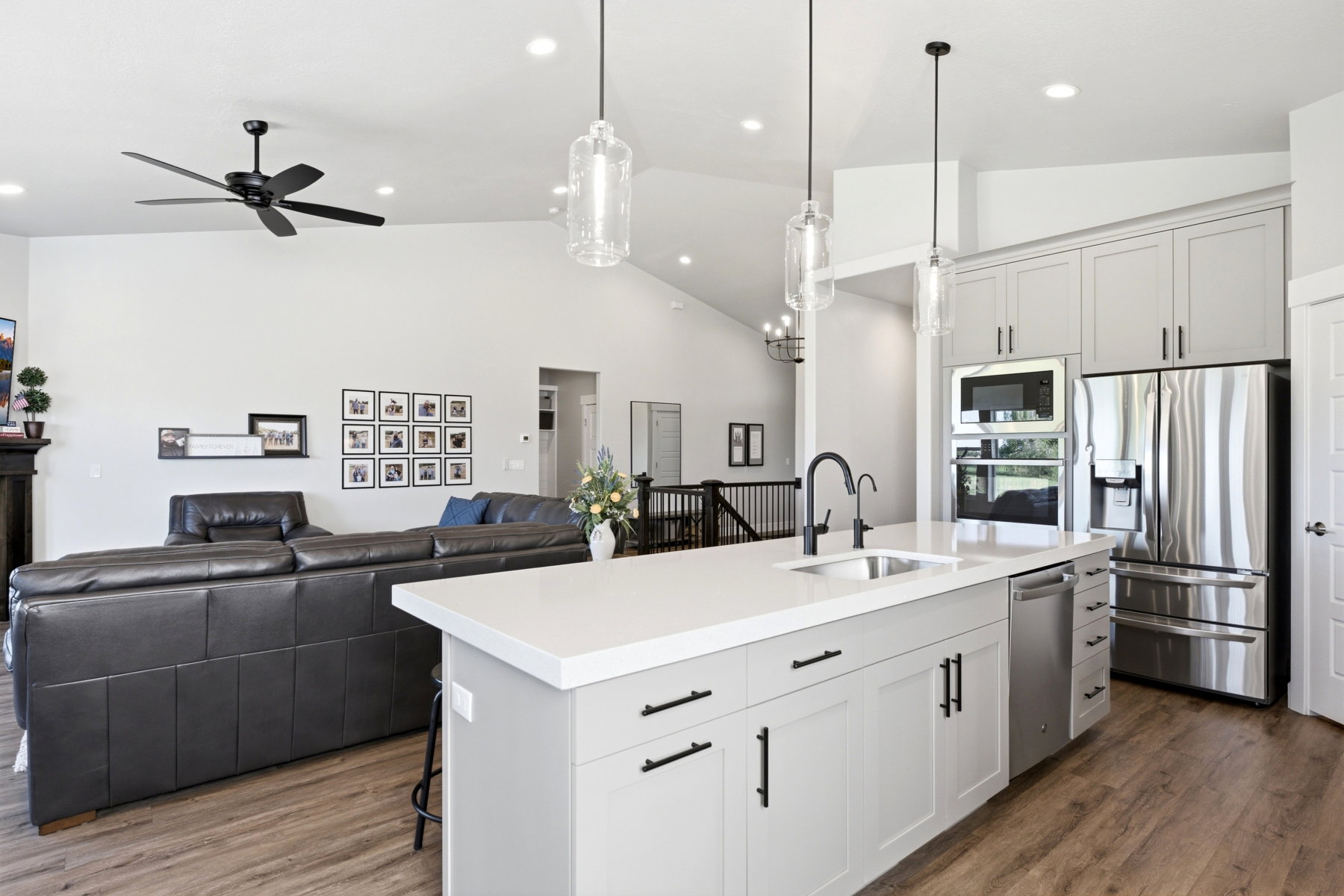 Kitchen island featuring a Quartz countertop, undermount sink with a black gooseneck faucet, and gray shaker-style cabinetry with black hardware