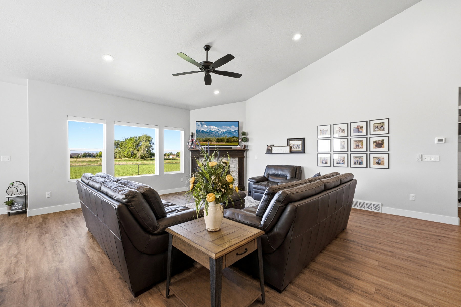 Spacious living area featuring high vaulted ceilings, multiple large windows, recessed lighting, and gas fireplace