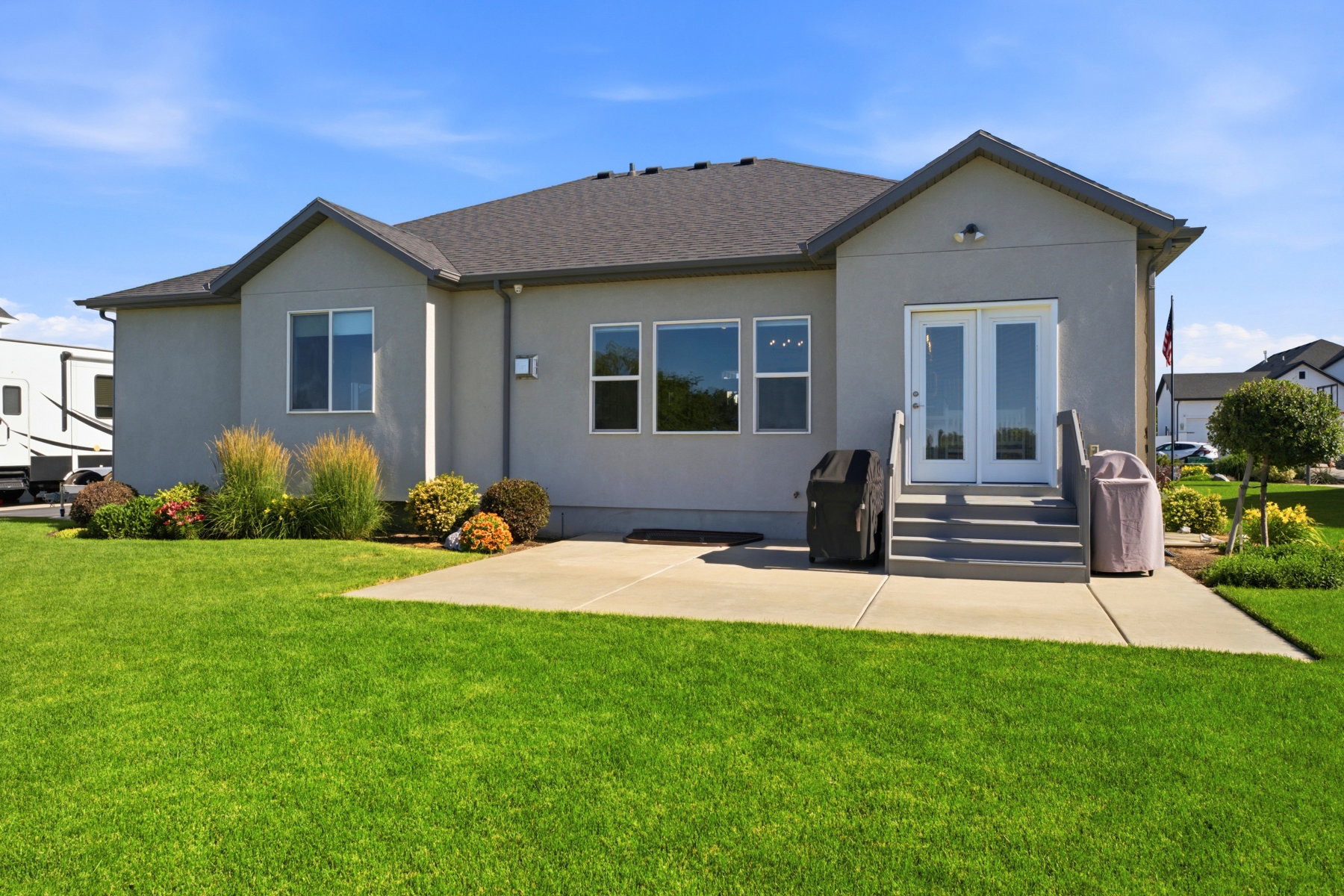 Expansive lawn area featuring a concrete patio, exterior double doors