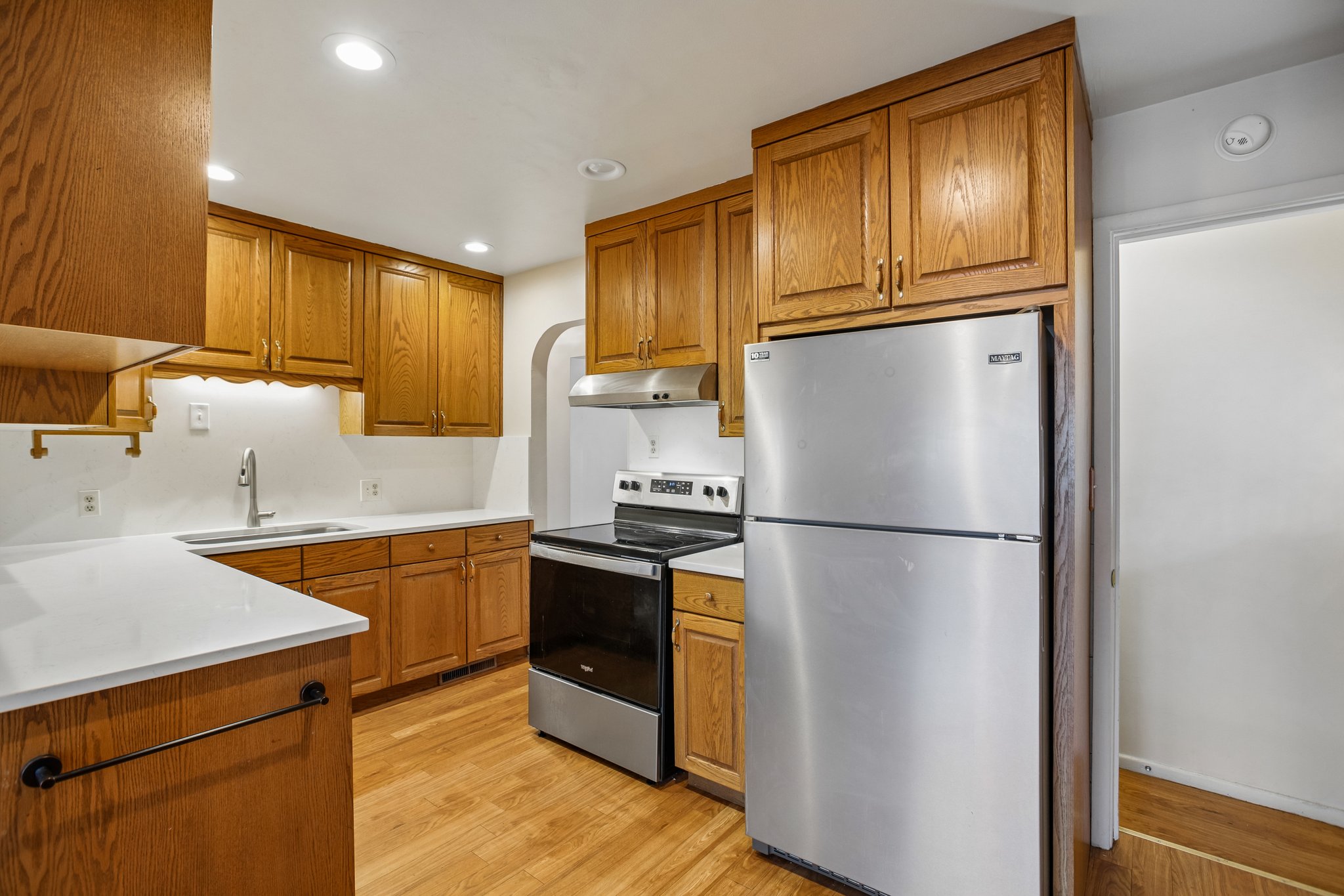 Kitchen featuring wood cabinetry, white countertops, stainless steel appliances, and wood-finish flooring