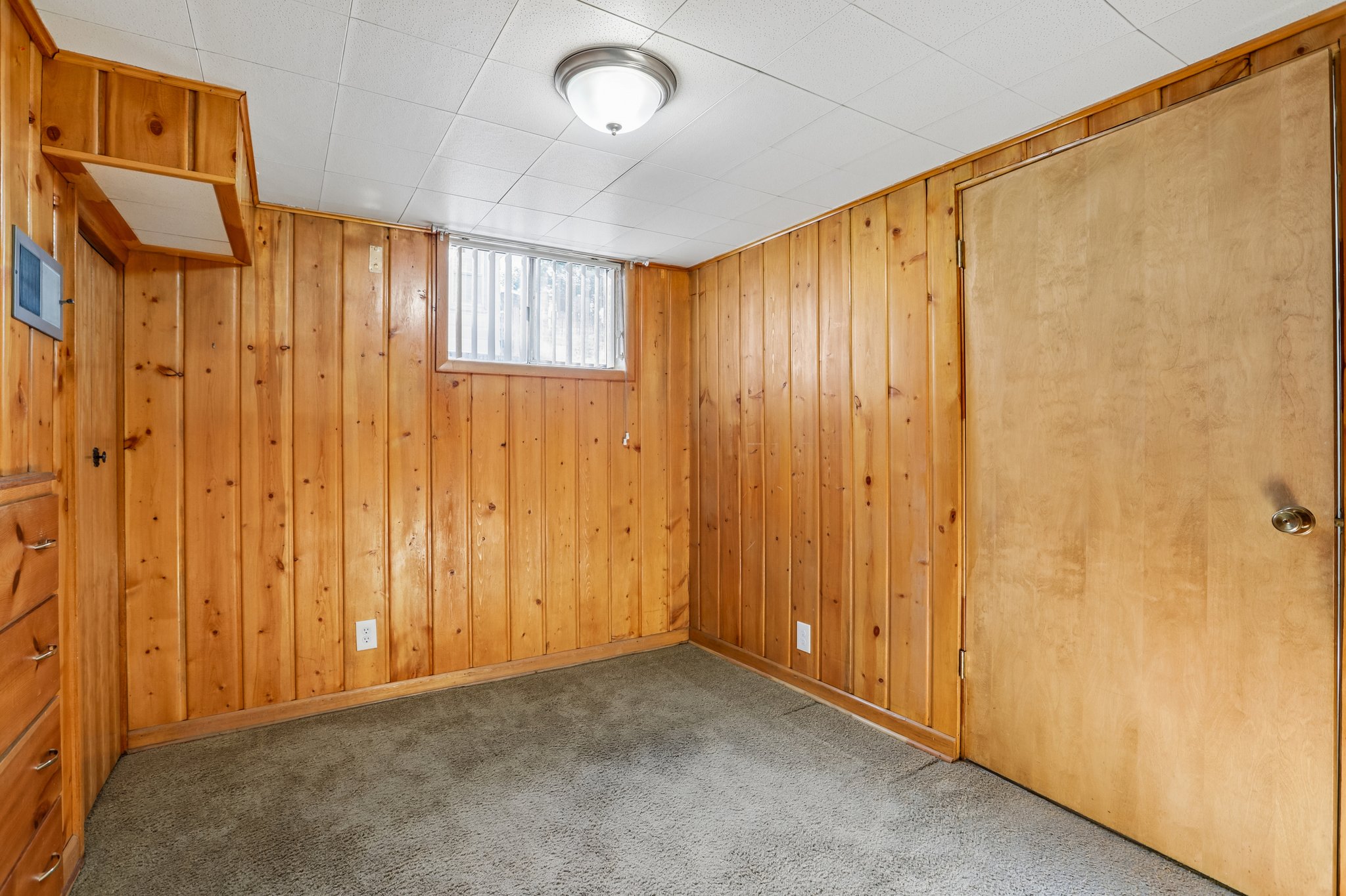 Room with wood-panel walls, drop ceiling, and wall-to-wall carpeting