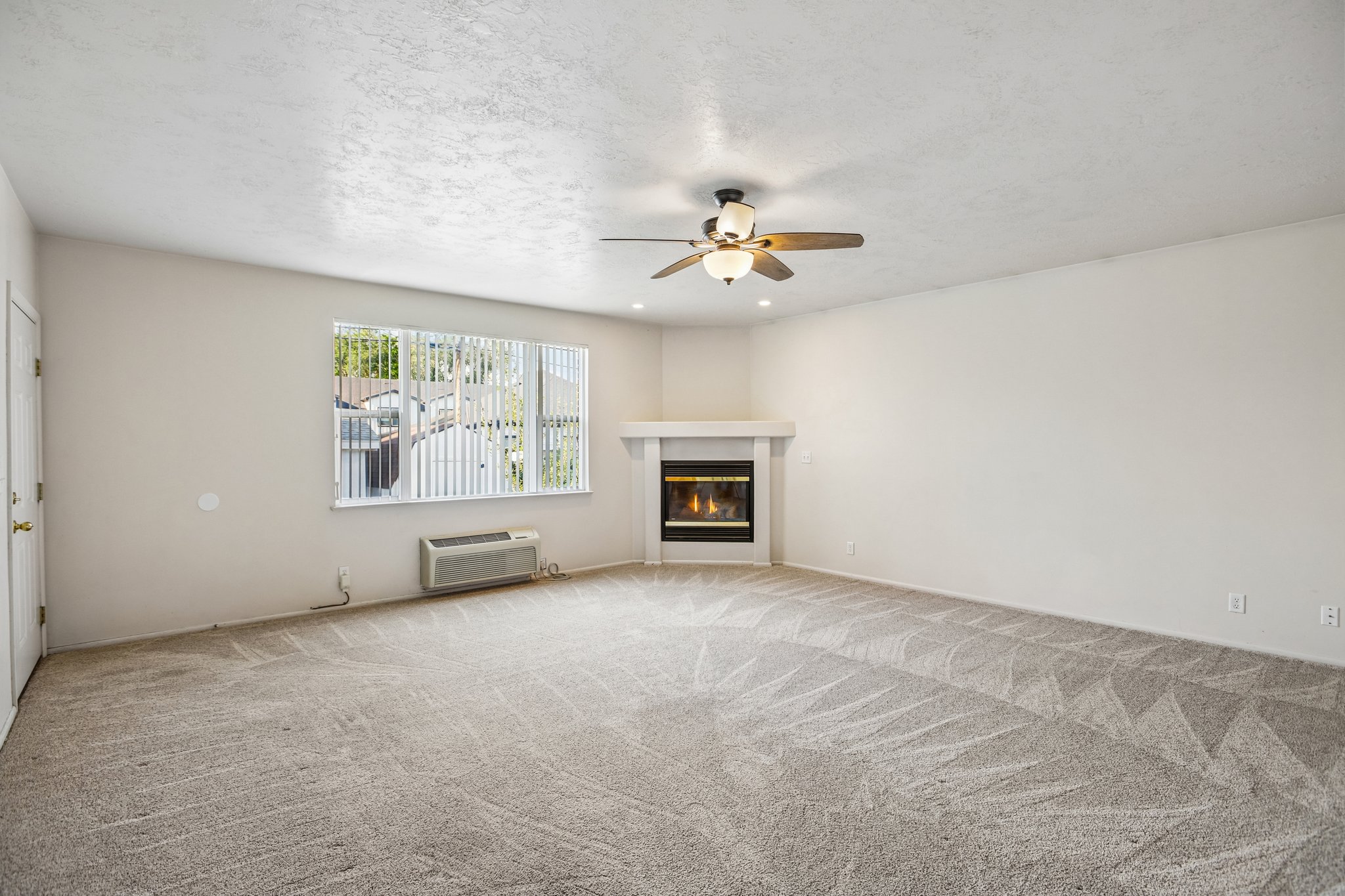 Spacious room featuring light-colored walls and patterned carpeting
