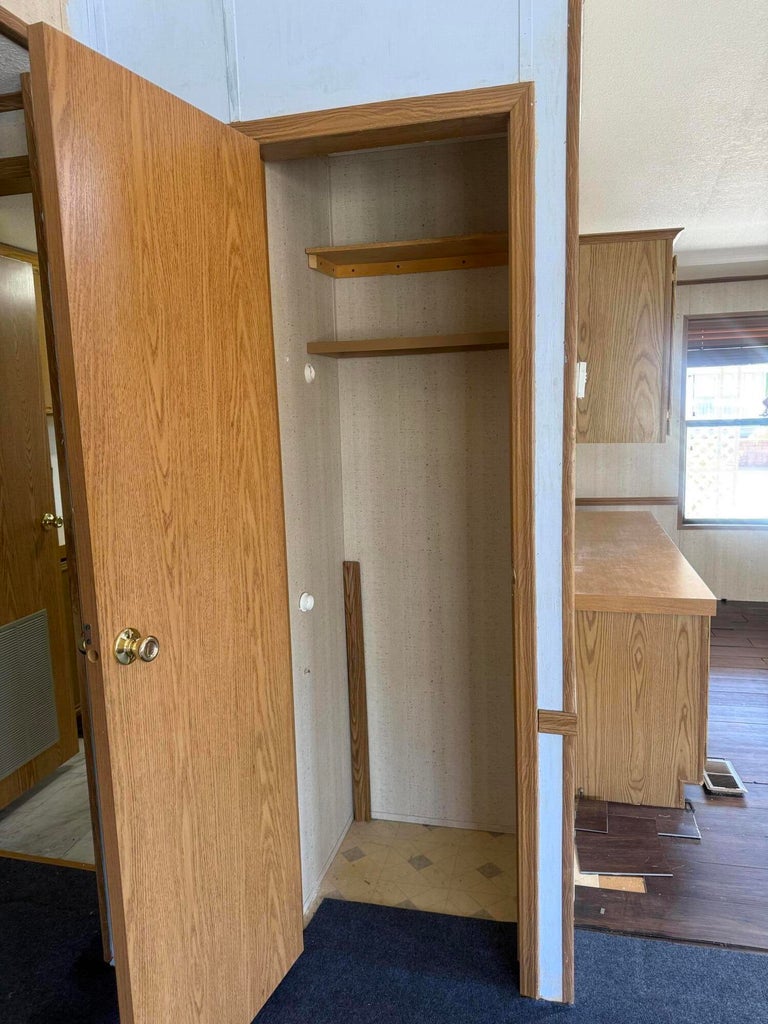 Recessed storage closet featuring wooden shelving and a wood-finish door