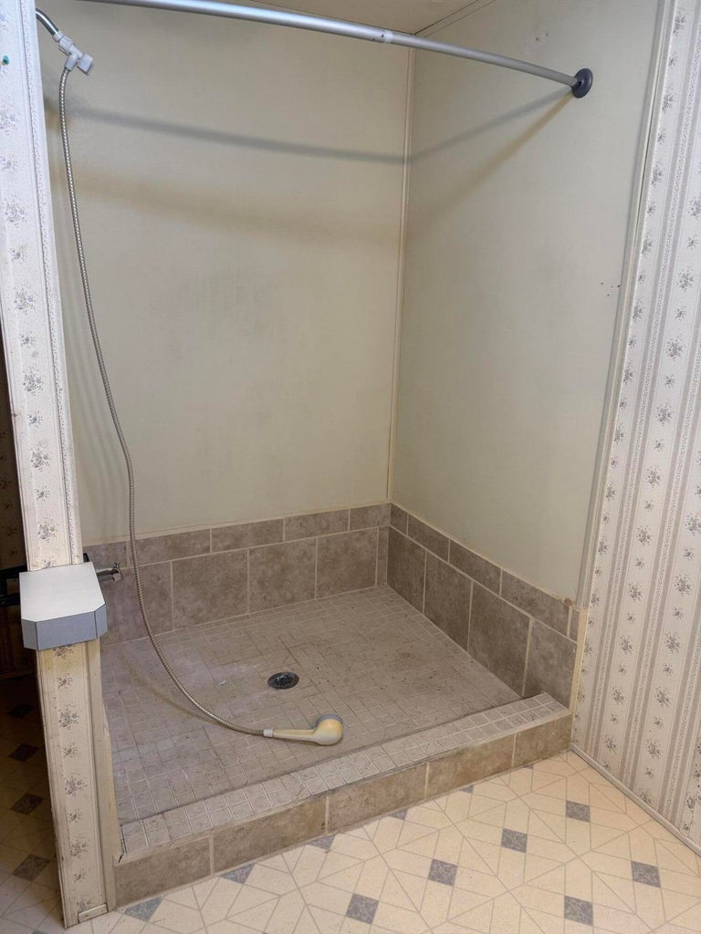 Walk-in shower featuring a handheld spray, tiled base, and coordinating tiled surround