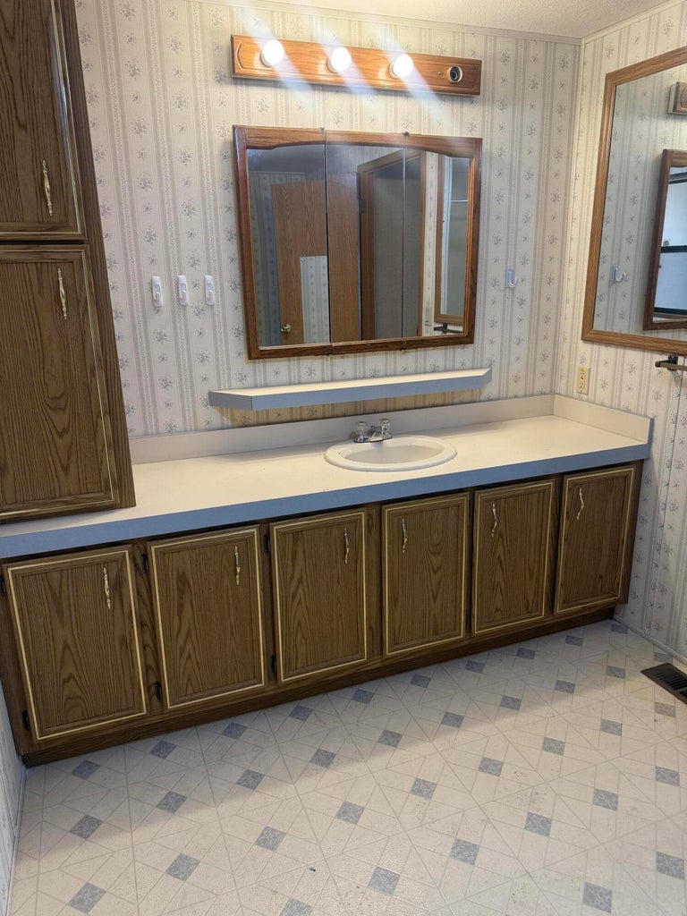 Bathroom featuring a wood-finish vanity with an integrated sink and light-toned countertop