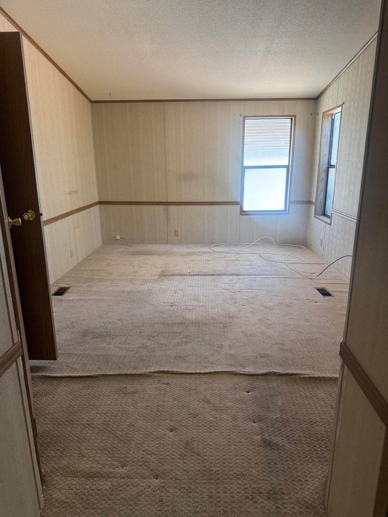 Room featuring two windows, neutral carpet, and paneled walls with wood trim