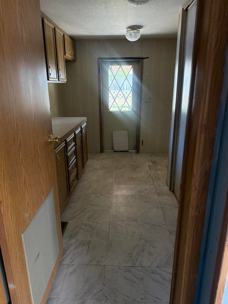 Kitchen area featuring wood-finish cabinetry, a light-toned countertop, and square tile flooring